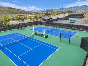 Tennis court complex featuring blue and green hard courts, perimeter fencing, and seating areas