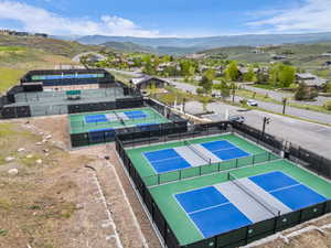Multiple outdoor sports courts, including several pickleball courts with blue and gray surfaces, and tennis courts with green surfaces