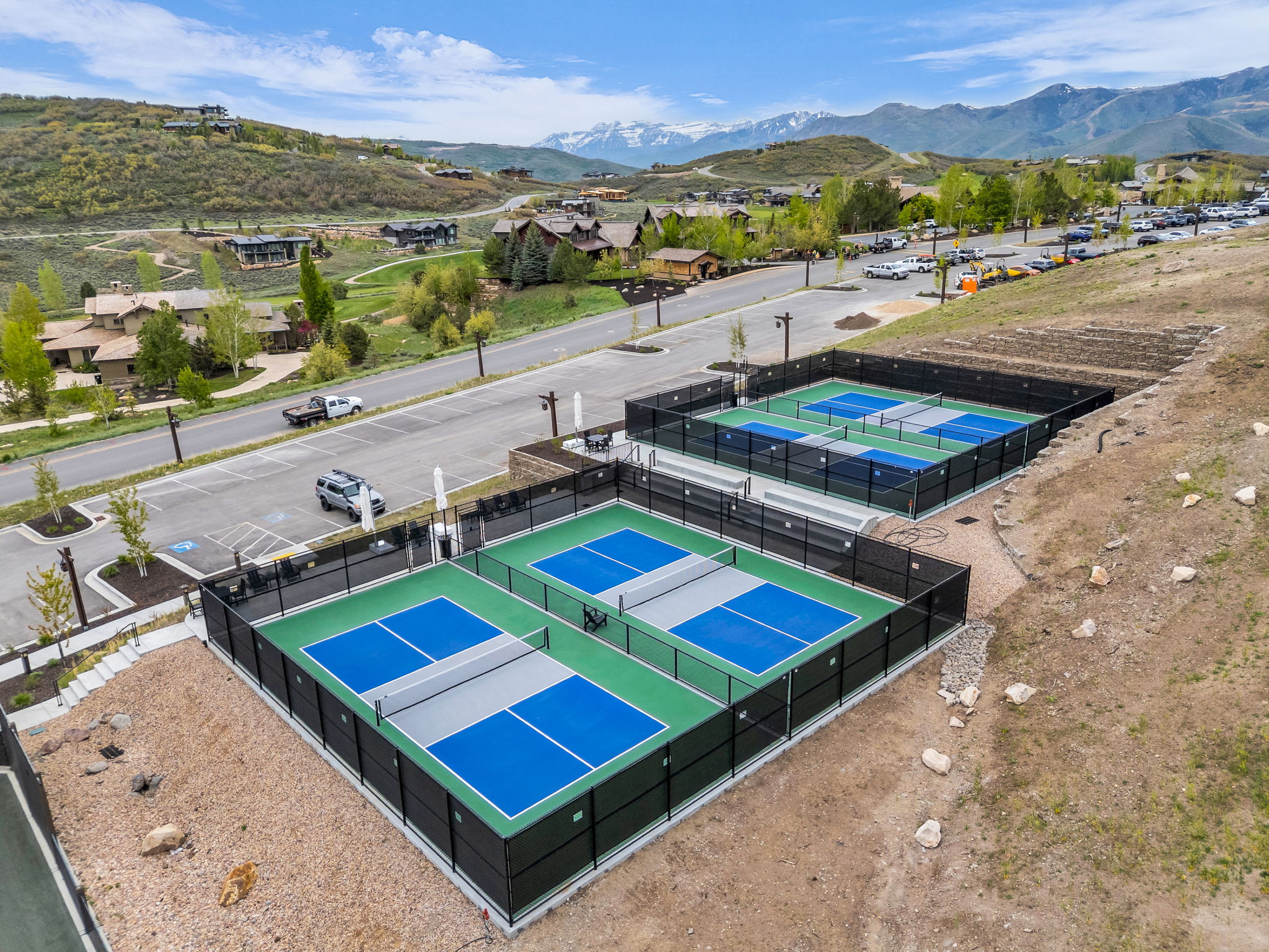 Multiple dedicated pickleball courts with black perimeter fencing and vibrant blue and green playing surfaces