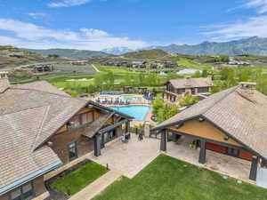 Expansive outdoor pool area with surrounding lounge seating, framed by gabled buildings with stone chimneys and wood siding