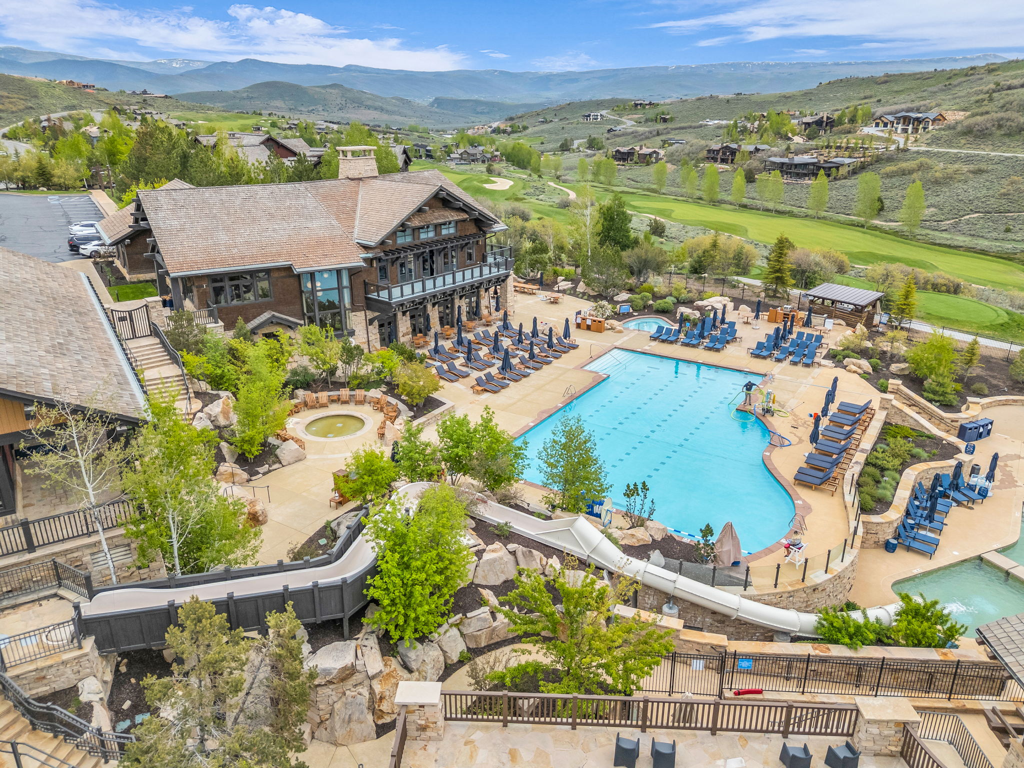 Expansive outdoor aquatic area featuring a large swimming pool, leisure pool, and water slide
