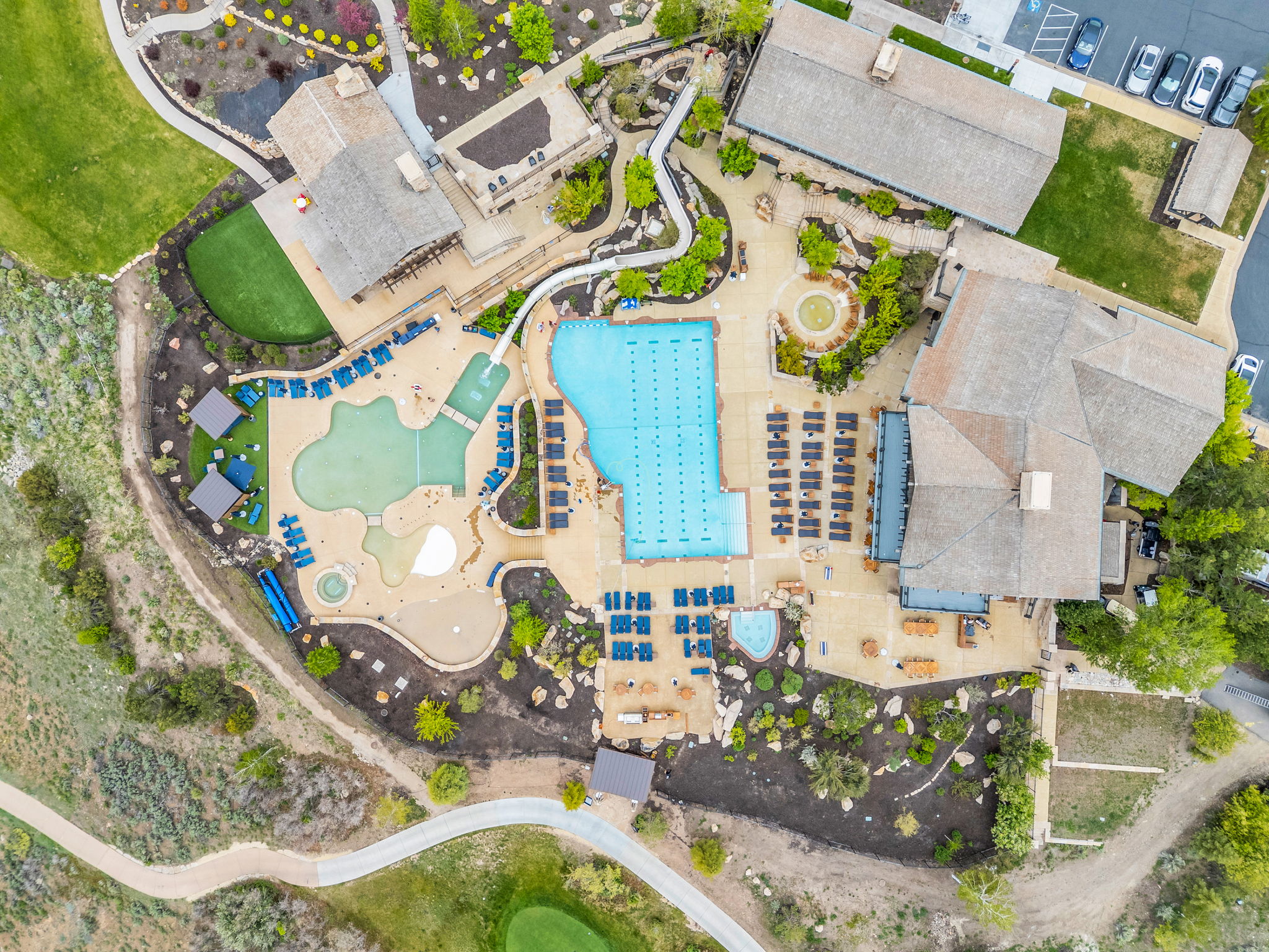 Community recreation area featuring multiple swimming pools, extensive patio decking, and surrounding landscaped grounds