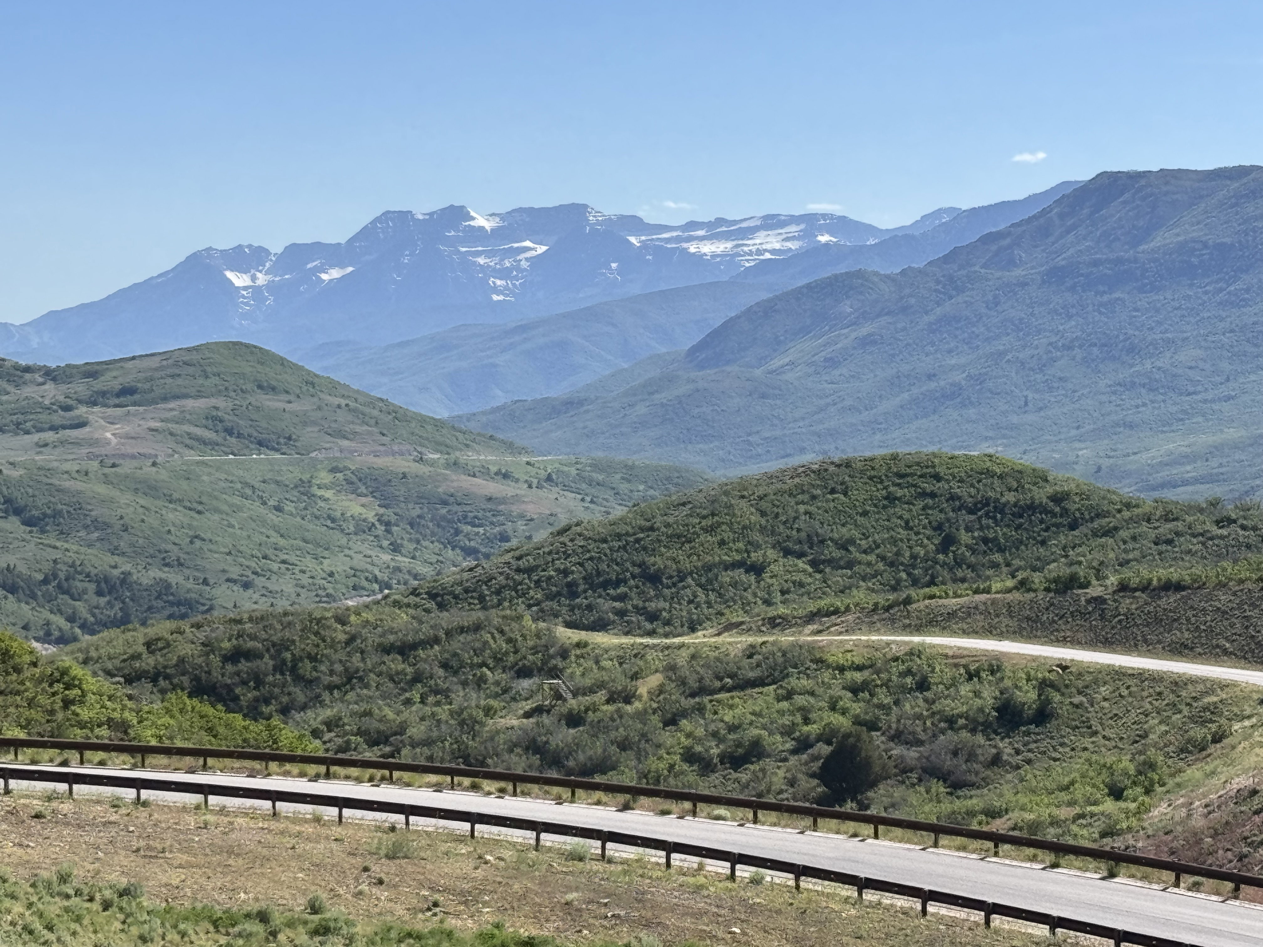 Expansive mountain scenery featuring rolling green hills and distant snow-capped peaks