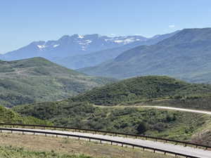 Expansive mountain scenery featuring rolling green hills and distant snow-capped peaks