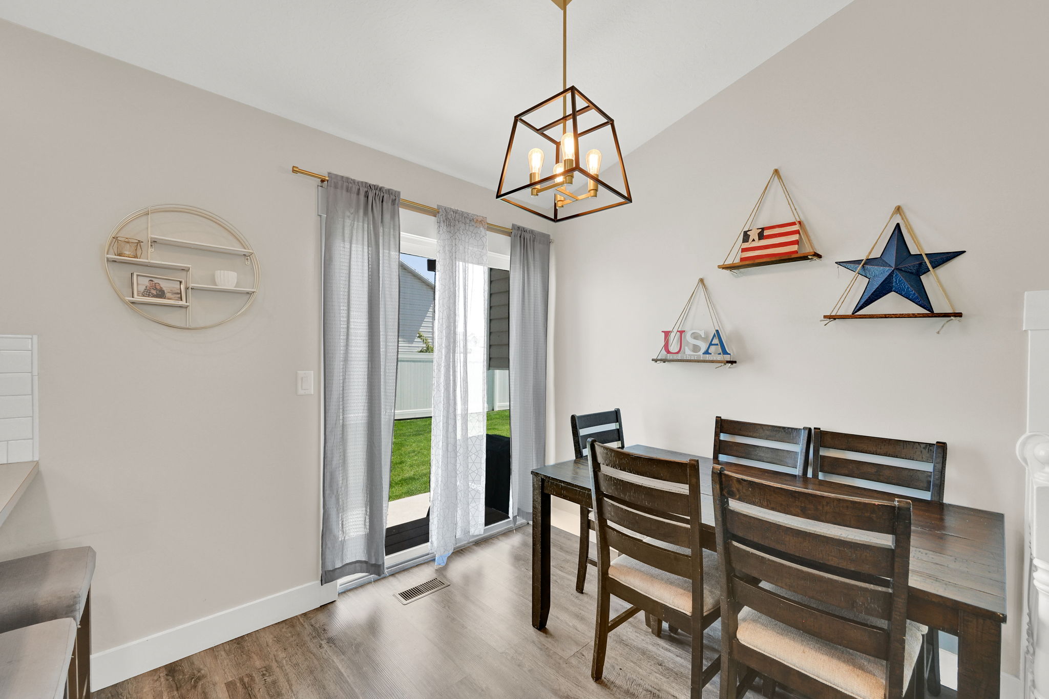 Dining area featuring a contemporary geometric chandelier, wood-finish flooring, and white baseboards