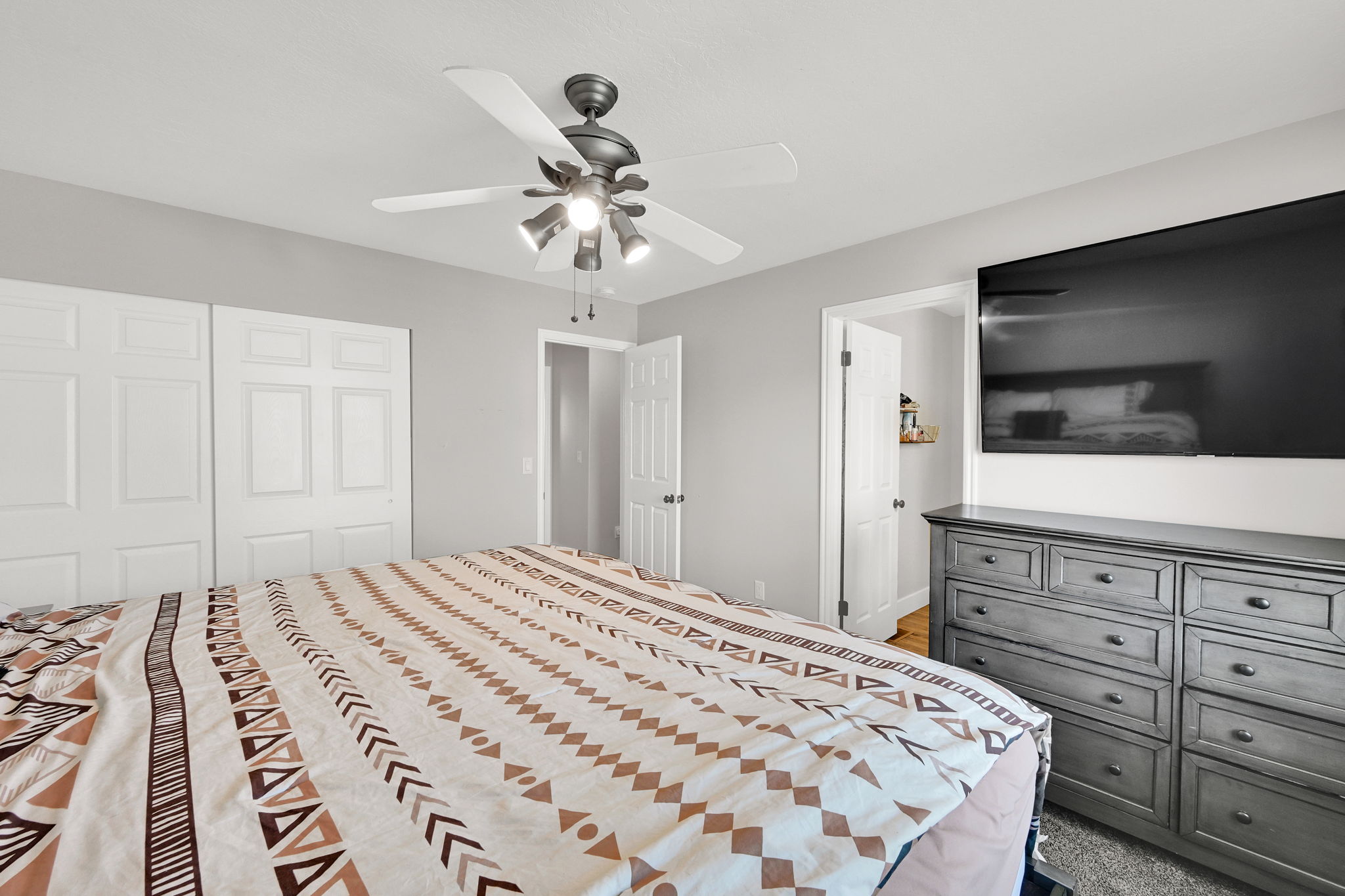 Bedroom featuring a ceiling fan with integrated lighting, paneled closet doors, and light gray wall paint