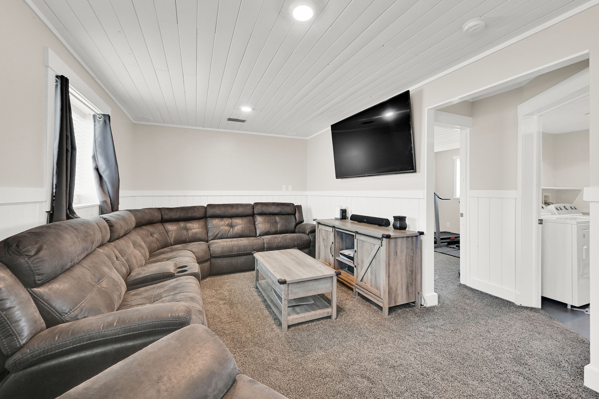 Carpeted living area featuring a white plank ceiling, white wainscoting, and recessed lighting
