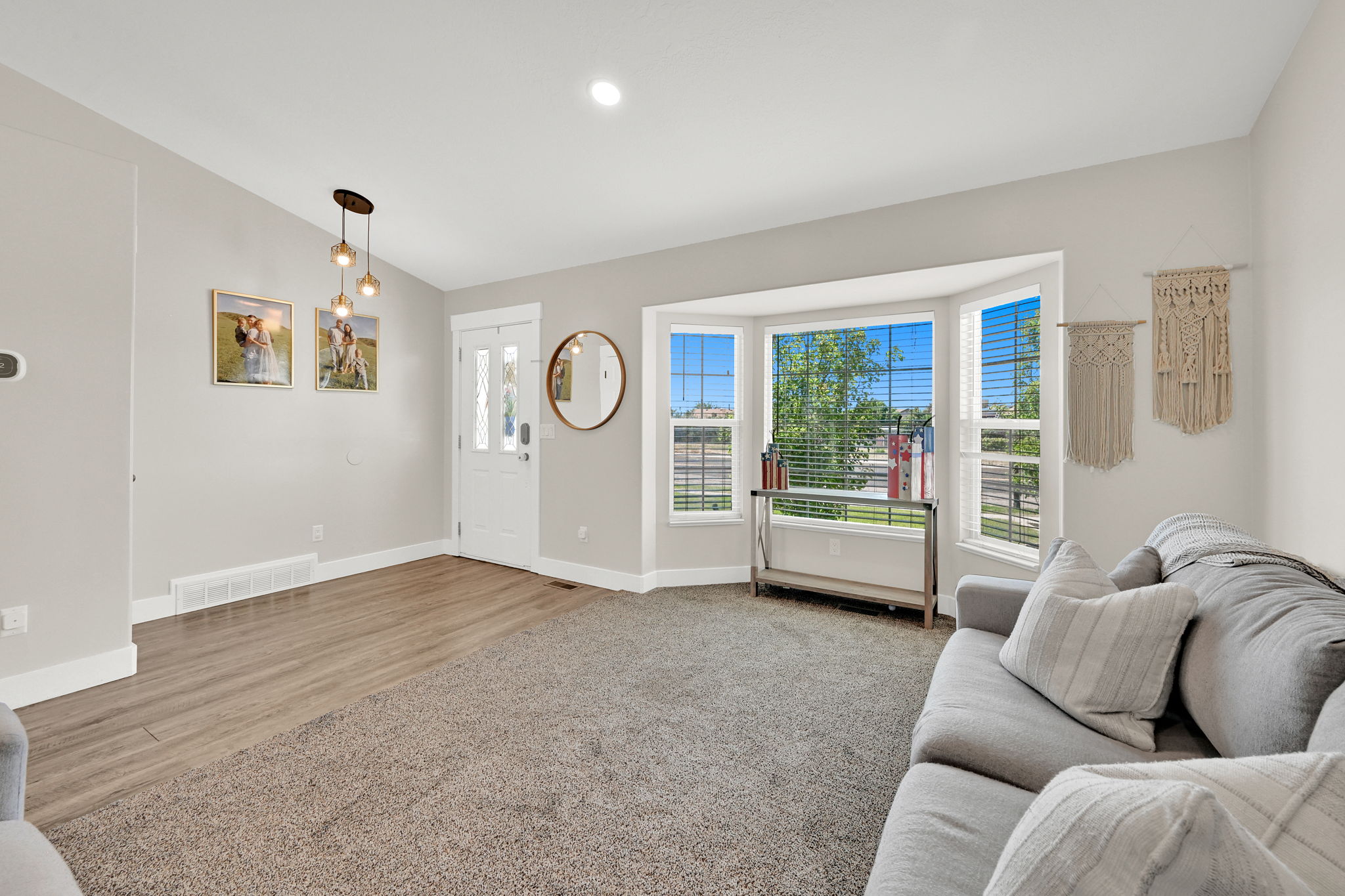 Bright living area featuring a bay window, wood-finish flooring, recessed lighting, and a front entry door with decorative glass panels