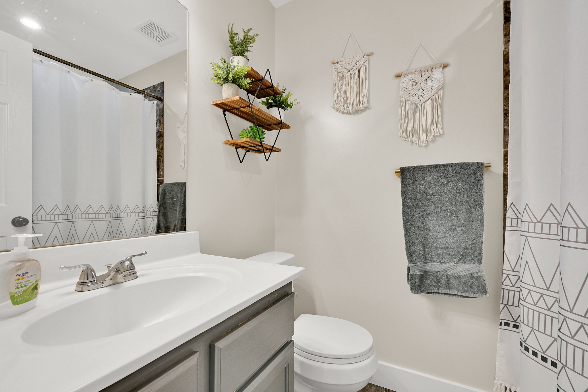 Bathroom featuring a vanity with an integrated sink and chrome faucet, a wall-mounted mirror, and a toilet