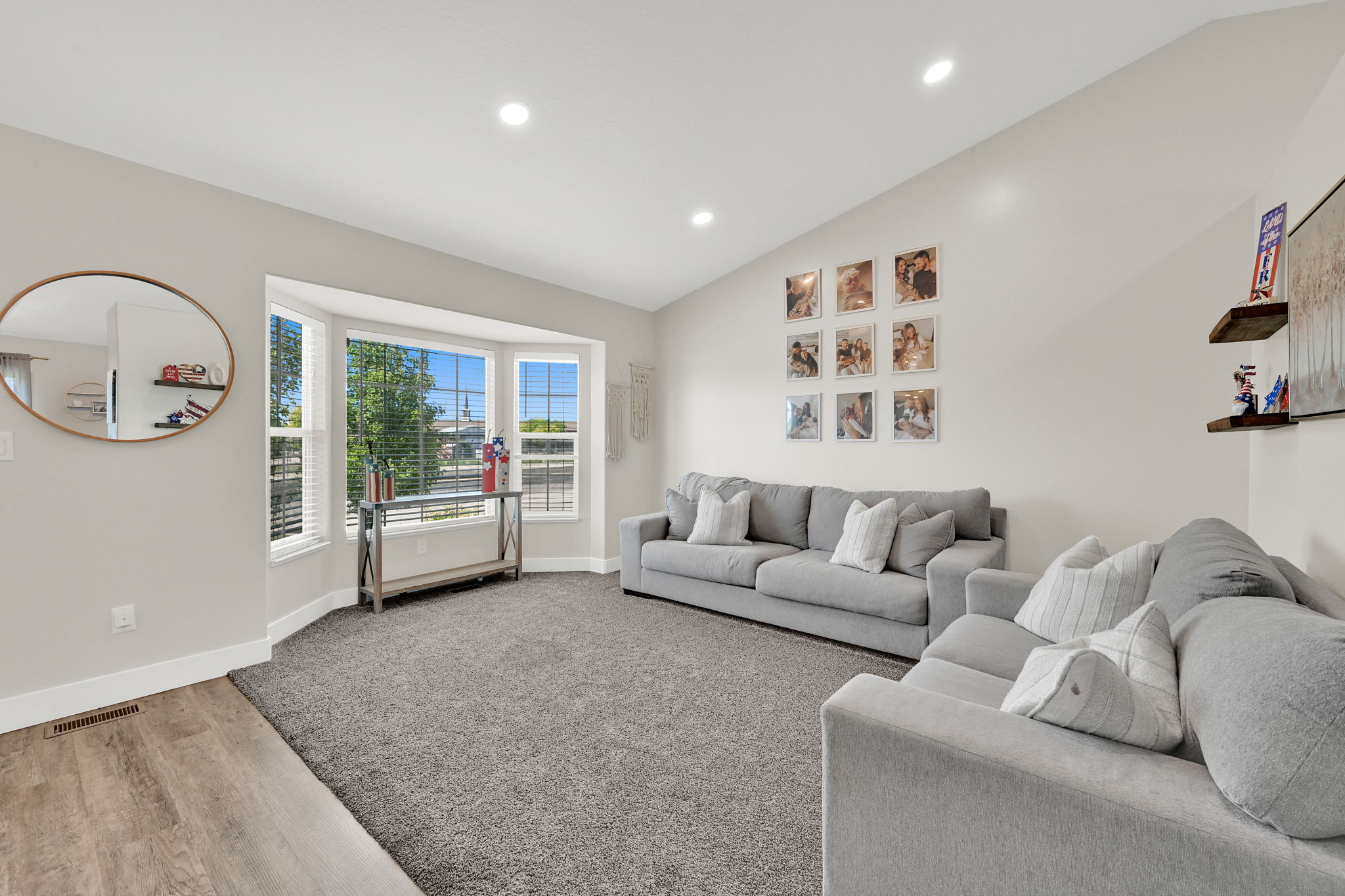 Living area featuring a bay window, recessed lighting, vaulted ceiling, wood-finish flooring, and plush carpeting