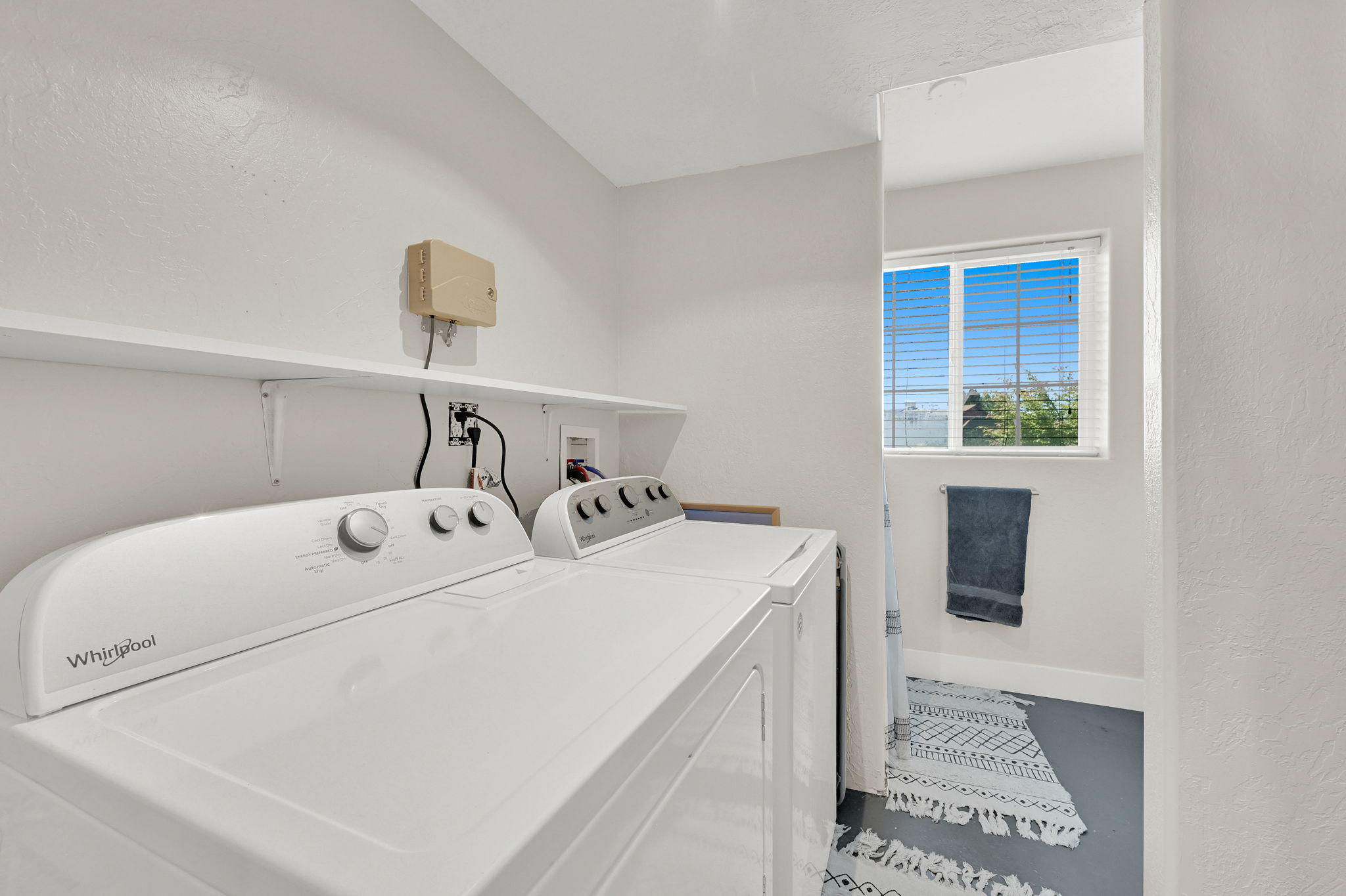 Dedicated laundry area featuring white walls and overhead shelving