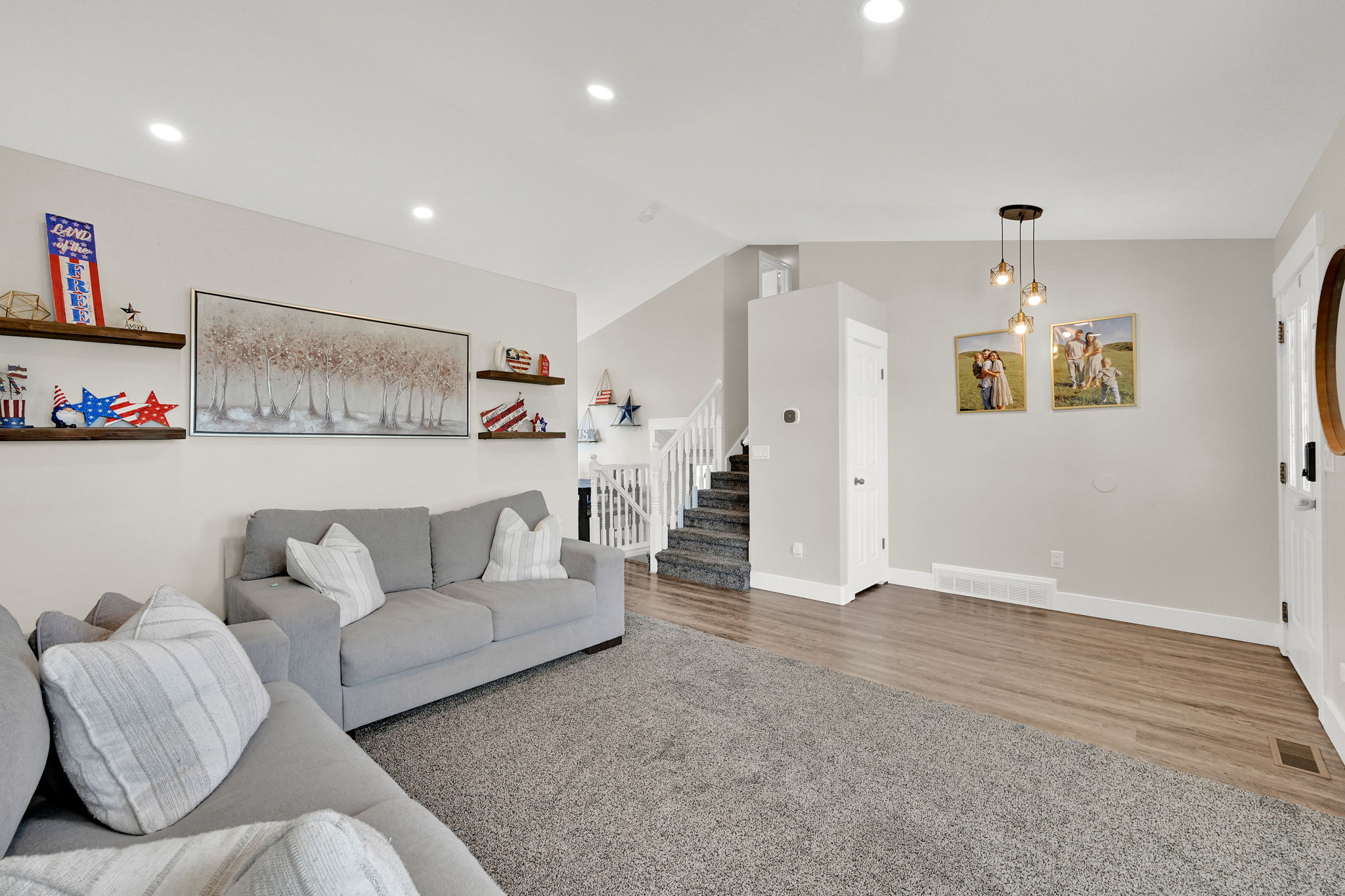 Open-concept living area featuring recessed lighting, wood-finish flooring, and a carpeted section
