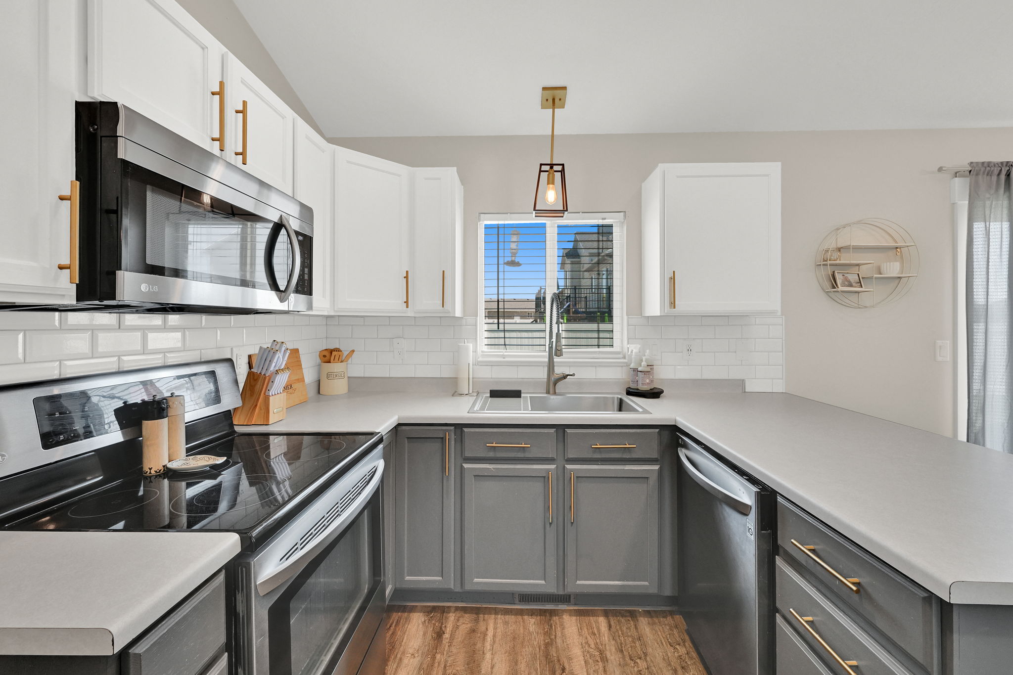Kitchen featuring a stainless steel oven and microwave, white subway tile backsplash, and two-tone cabinetry with gold-finish hardware