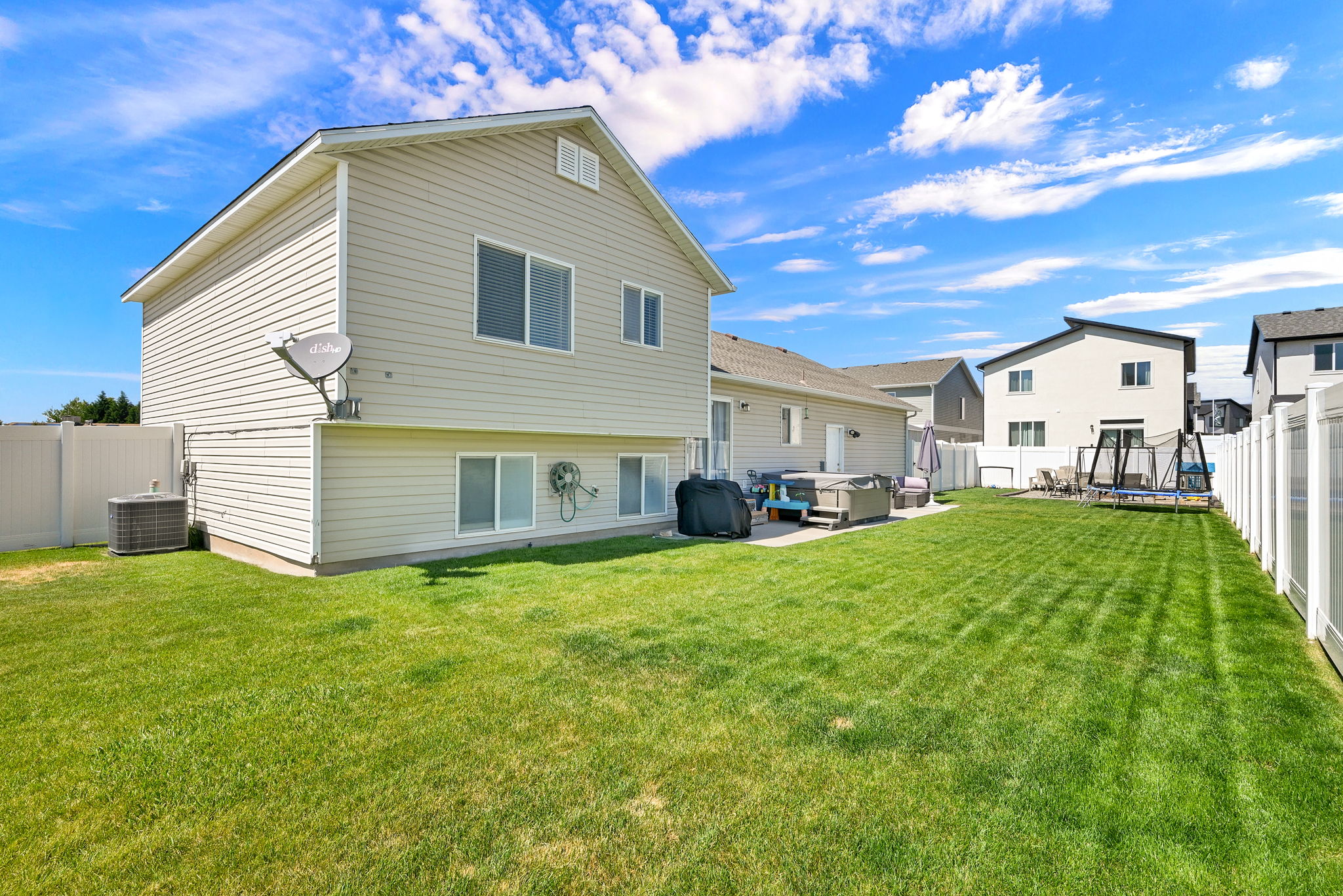 Expansive green lawn with a white vinyl fence enclosing the perimeter