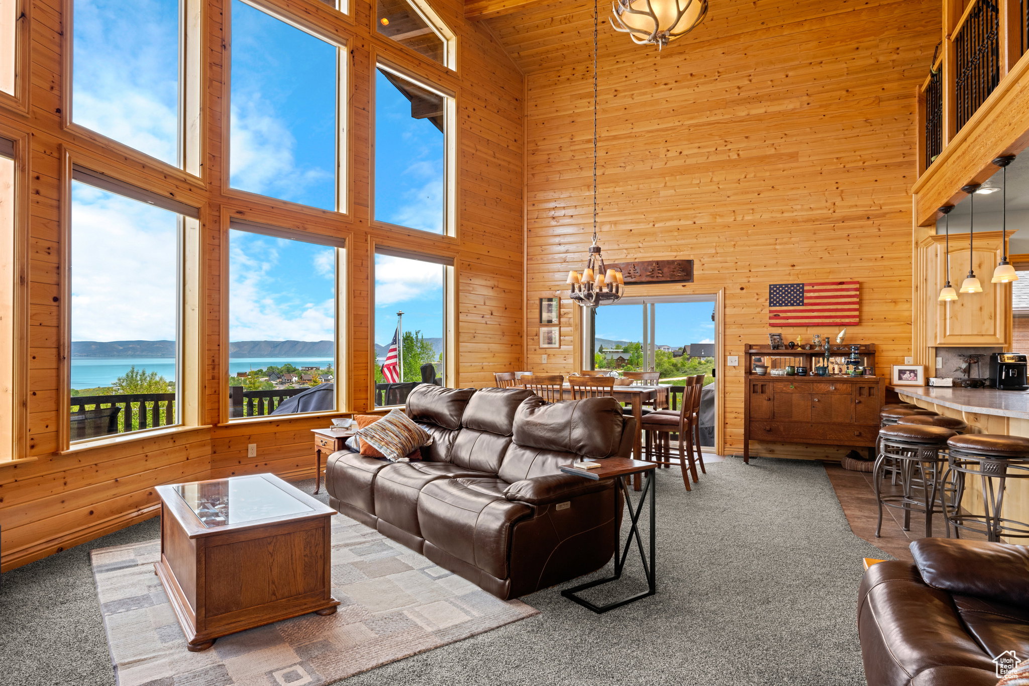 Great room featuring soaring ceilings, expansive window walls, wood paneling, and an open-concept layout