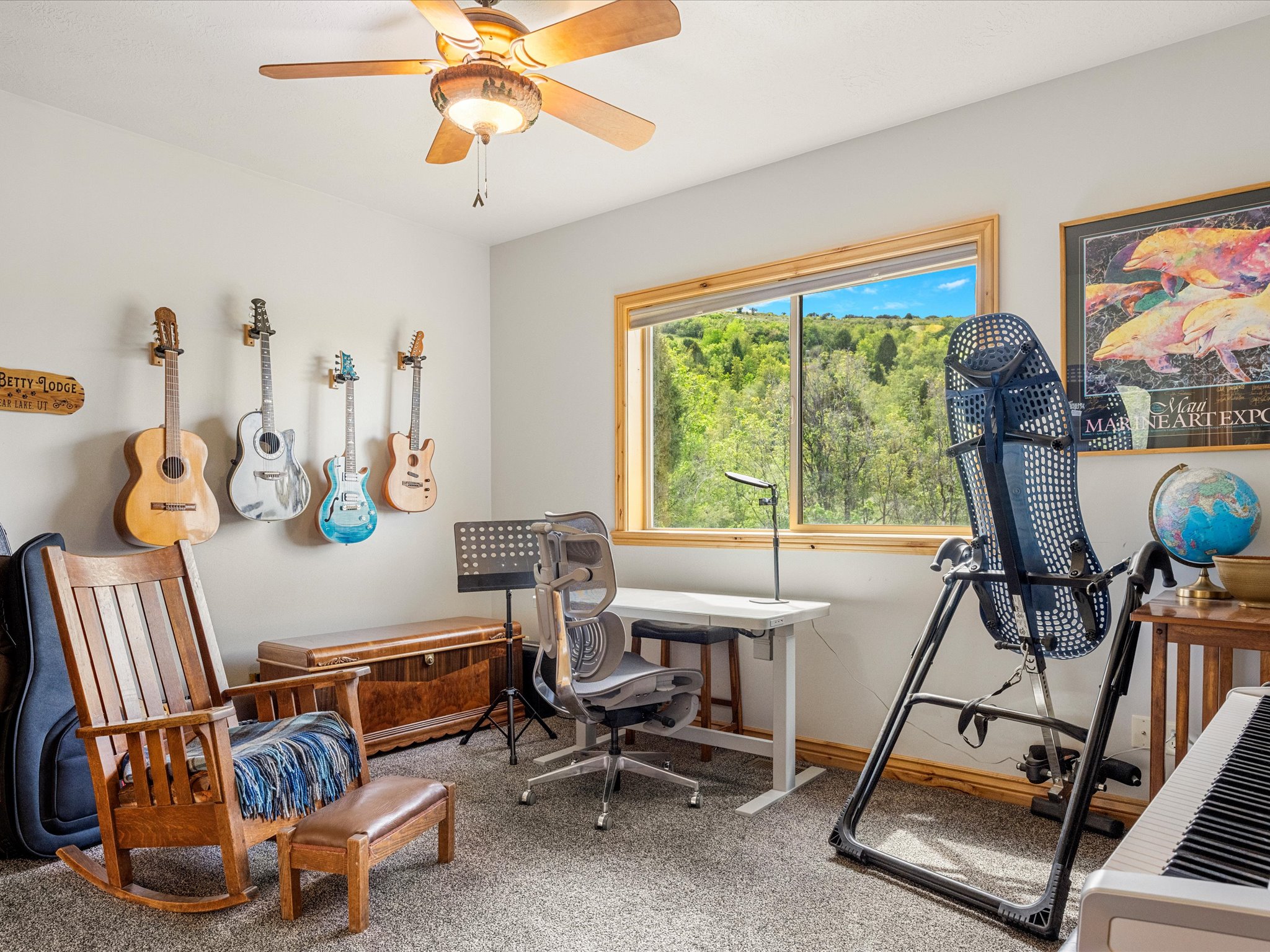 Carpeted room with a ceiling fan, a window with wood trim, and a serene outdoor backdrop