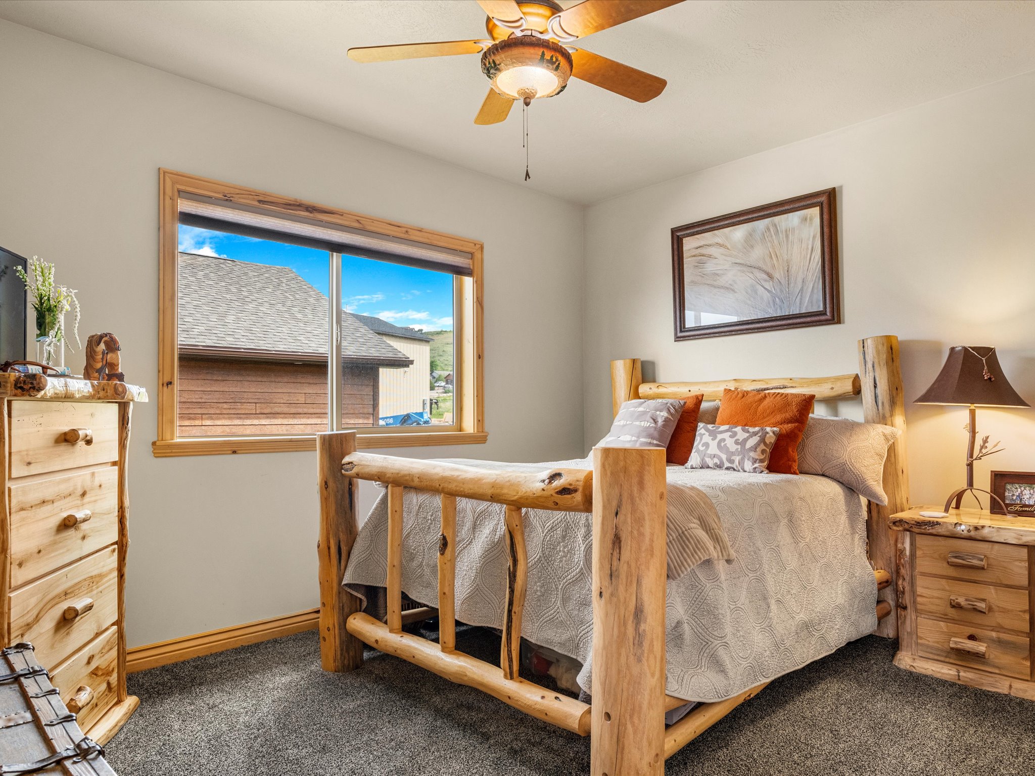 Bedroom featuring a window with wood trim, wood-finish ceiling fan with integrated lighting, and textured carpeting