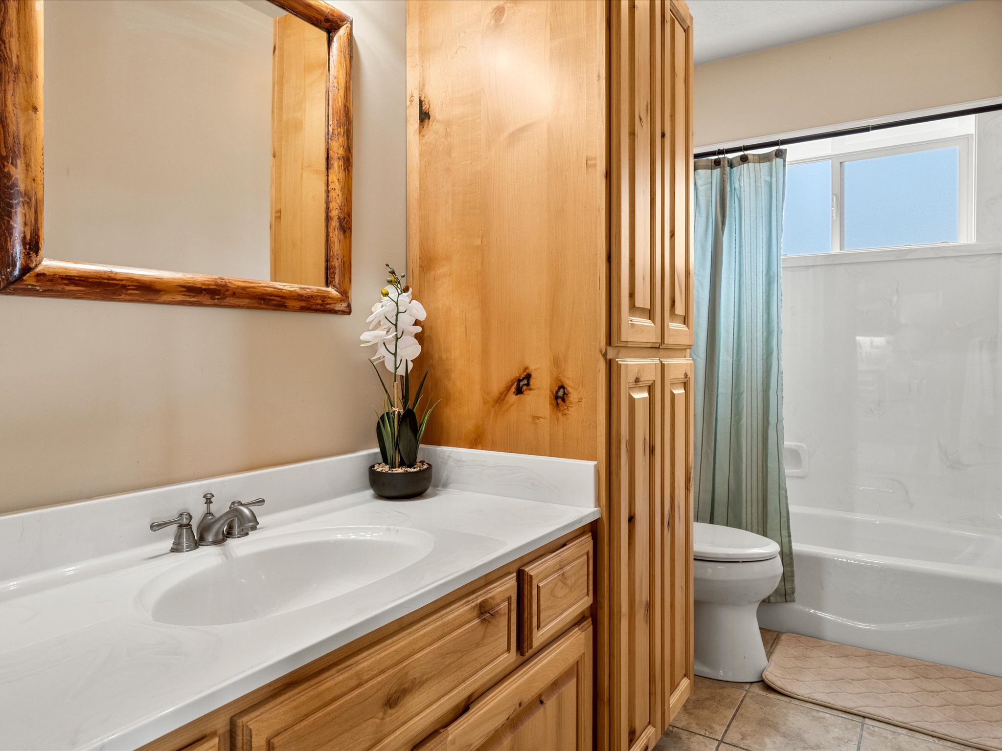 Bathroom featuring a wood-framed mirror, wood-finish vanity with an integrated sink, brushed nickel faucet, and natural wood cabinetry