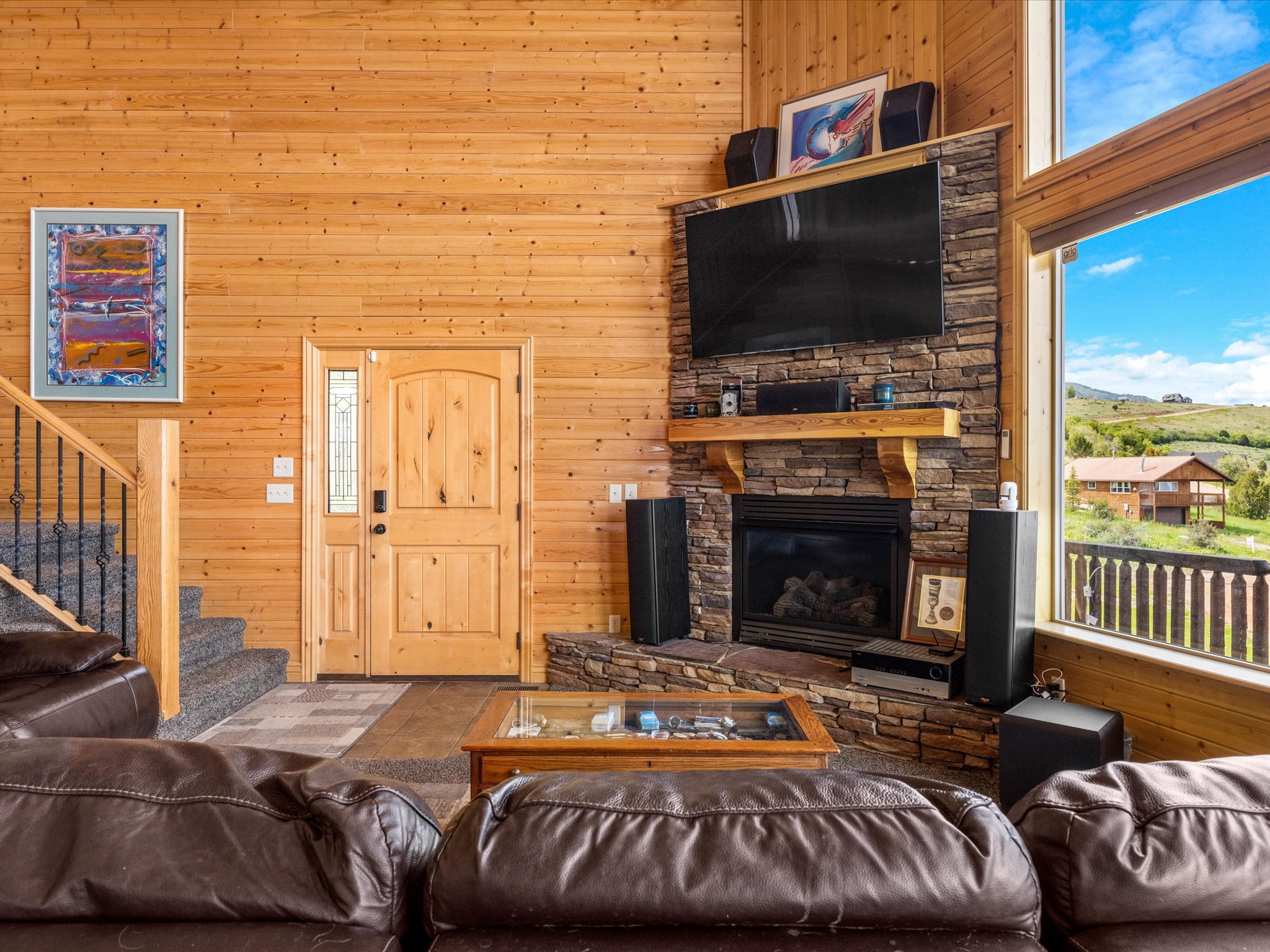 Great room featuring wood-finish walls and a stone-clad fireplace