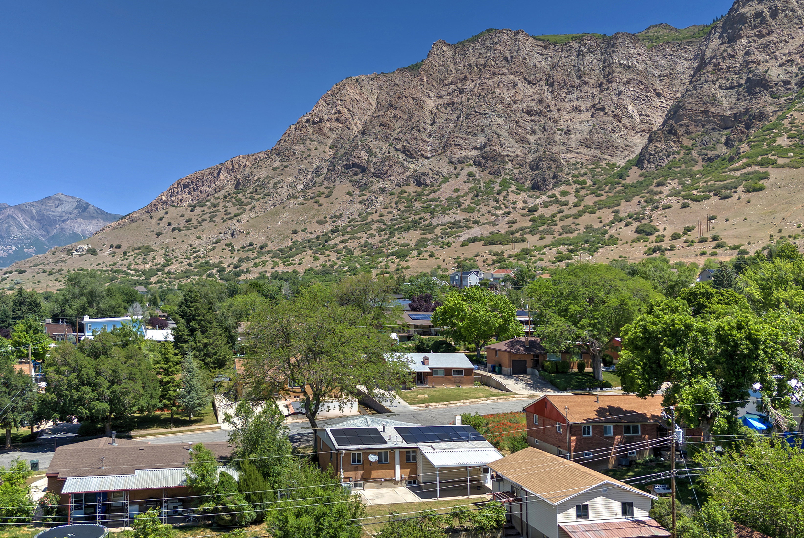 Expansive mountain backdrop with a residential area featuring mature trees and varied architectural styles