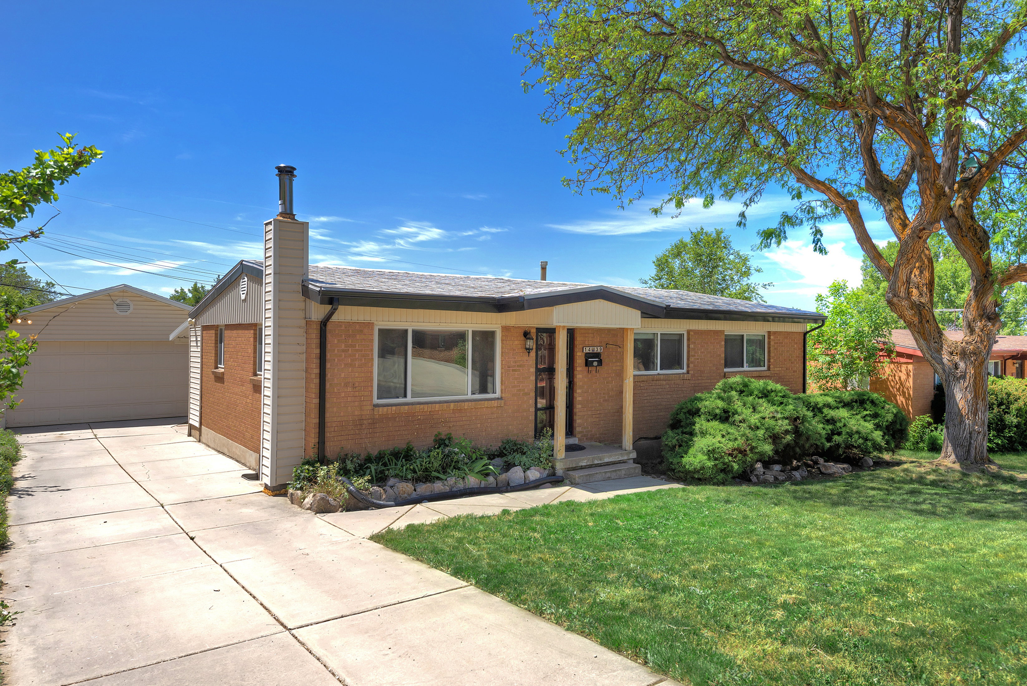 Brick exterior residence with a concrete driveway leading to a detached garage