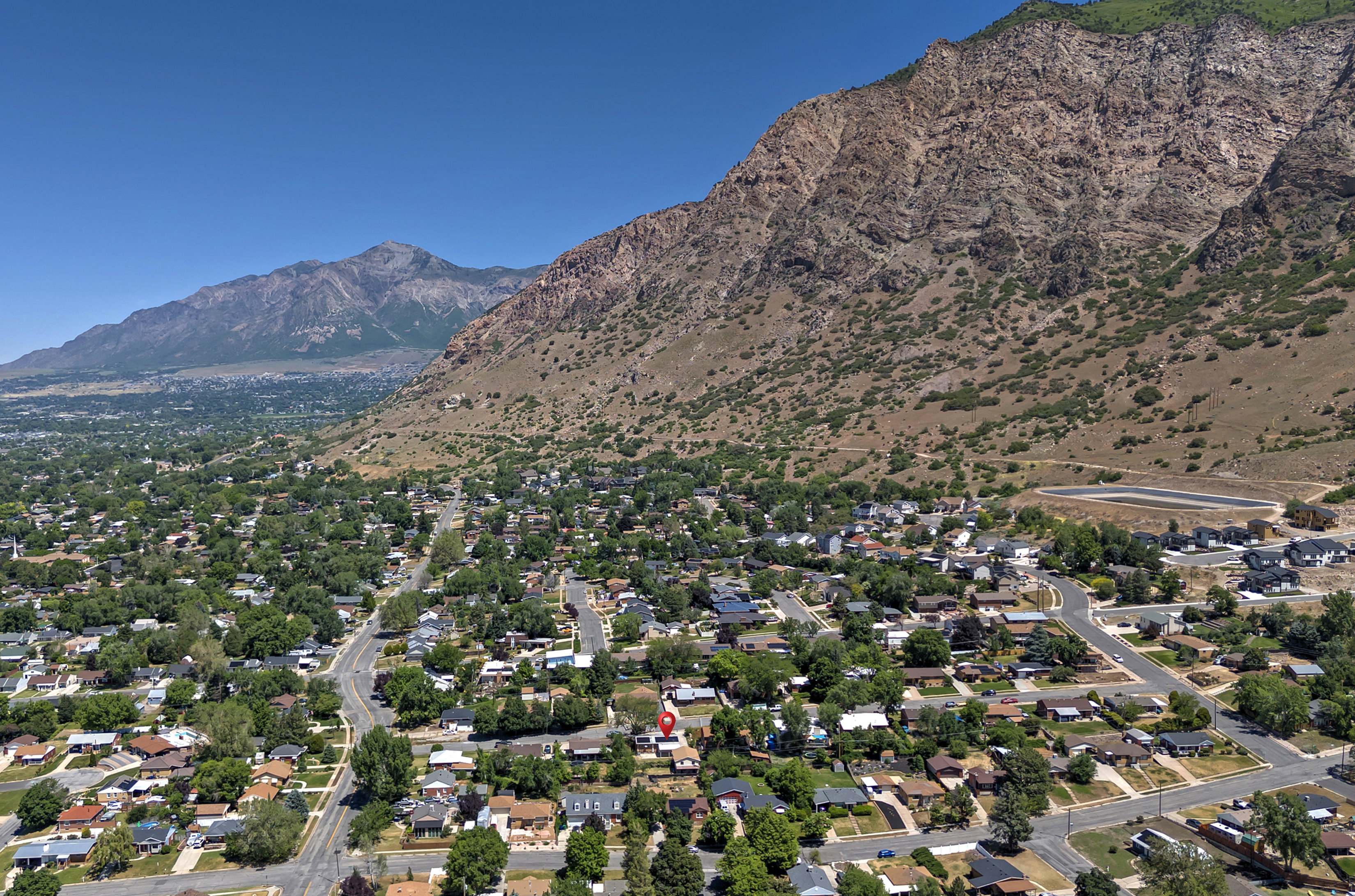 Expansive residential area featuring established homes and mature trees, set against a backdrop of mountainous terrain