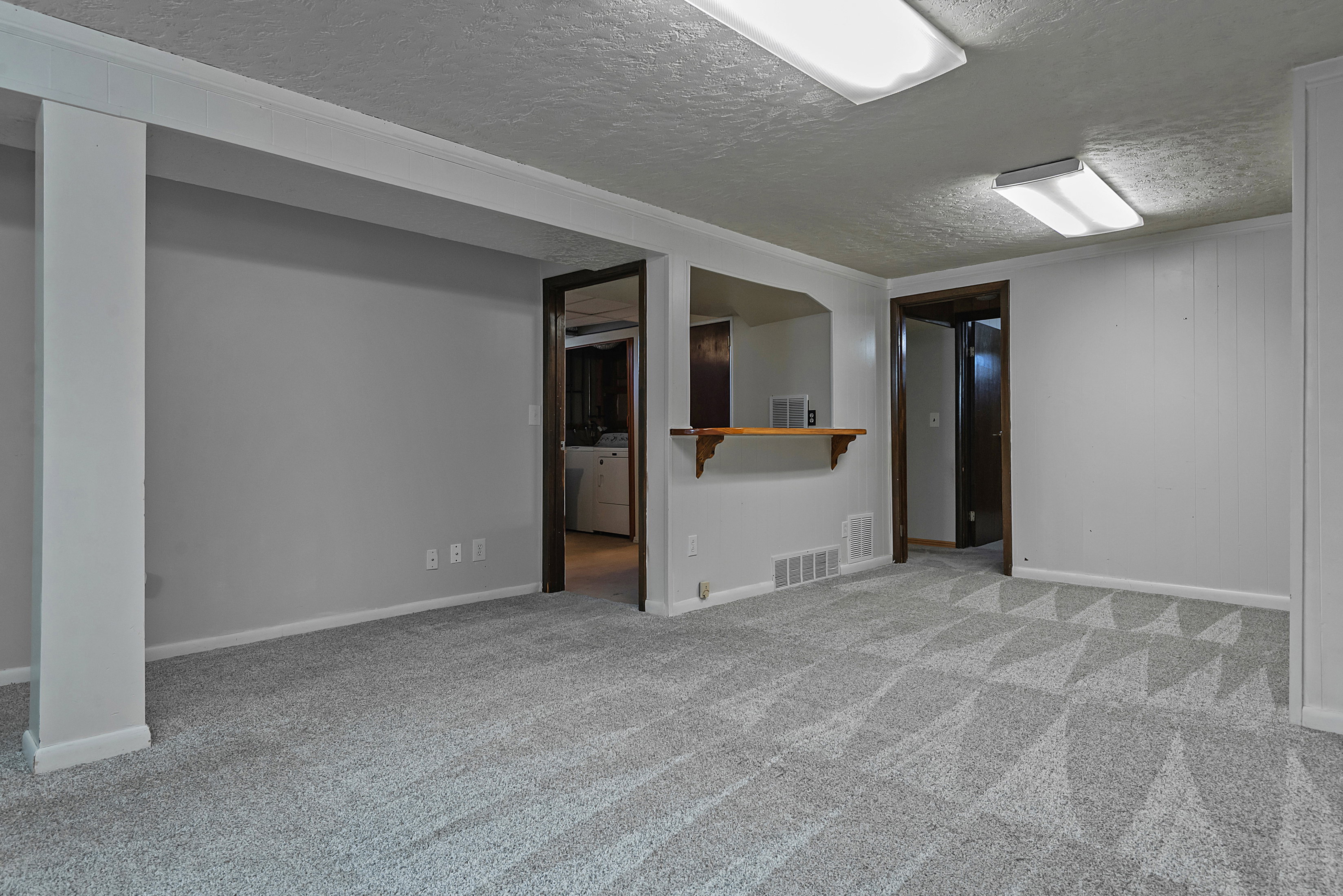 Spacious room featuring patterned gray carpet, light gray walls, and white trim