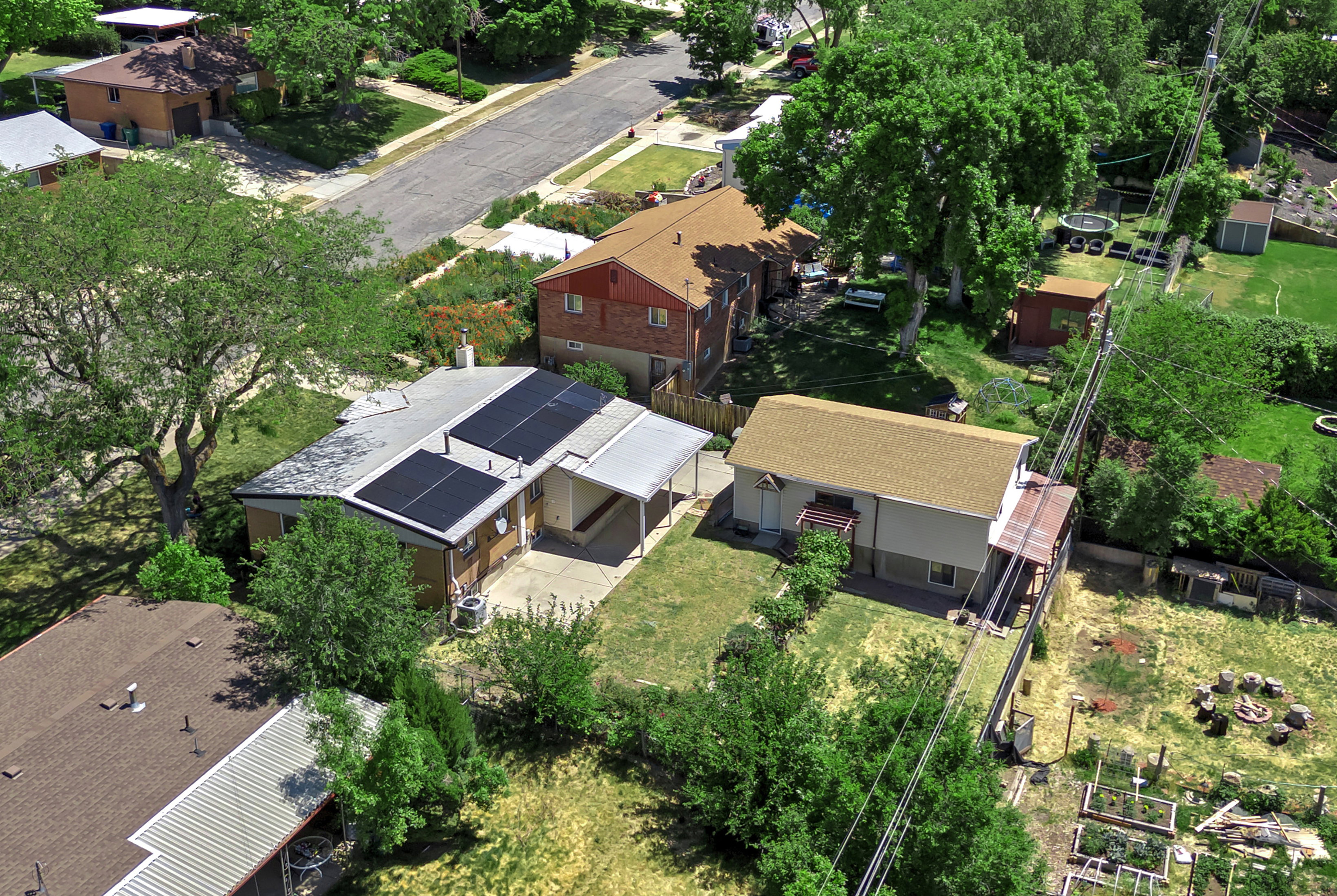 Property featuring a light-colored exterior with solar panels on the roof, an attached covered carport, and a paved driveway