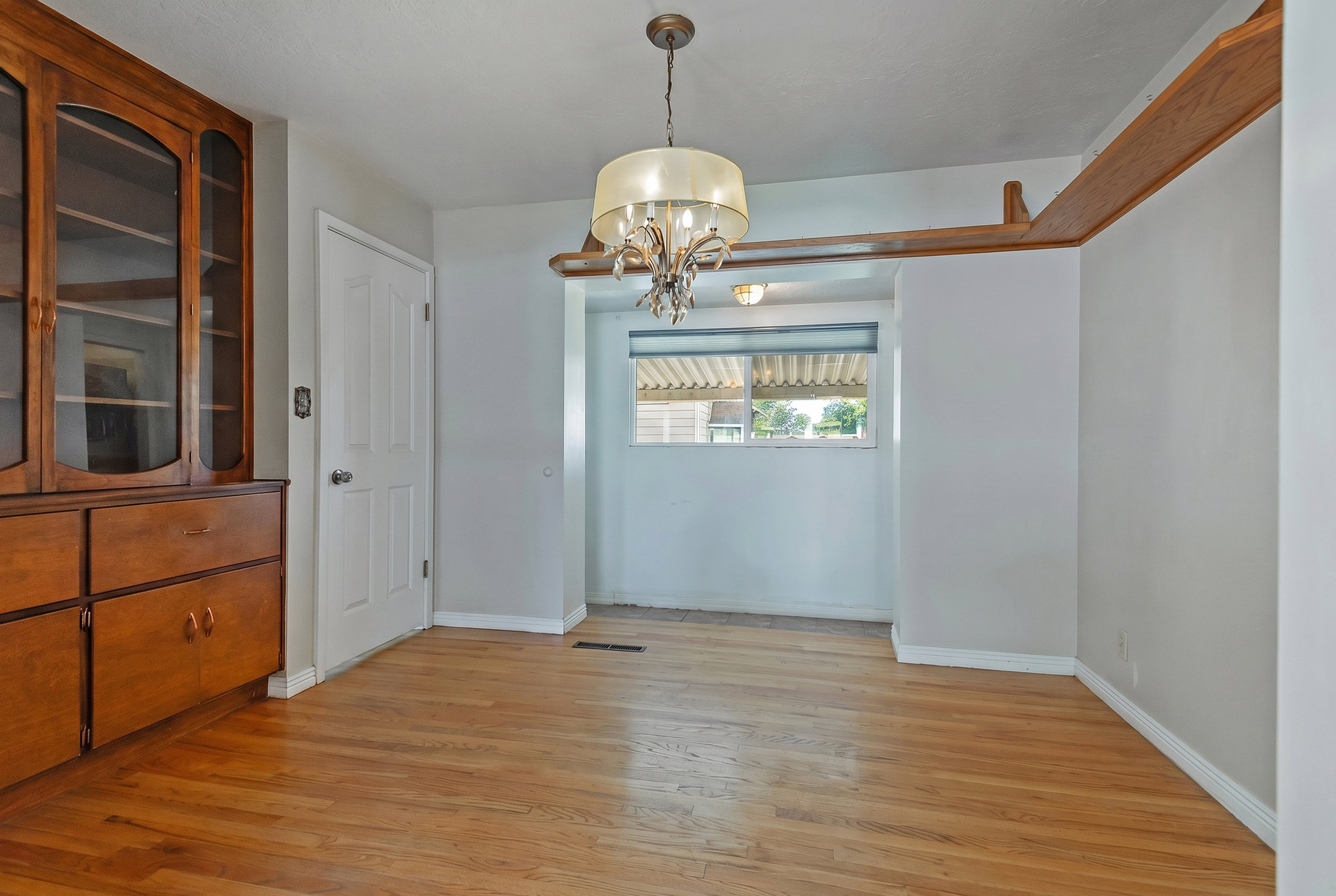 Wood-finish flooring throughout, complemented by a built-in wooden hutch with glass-fronted upper cabinets
