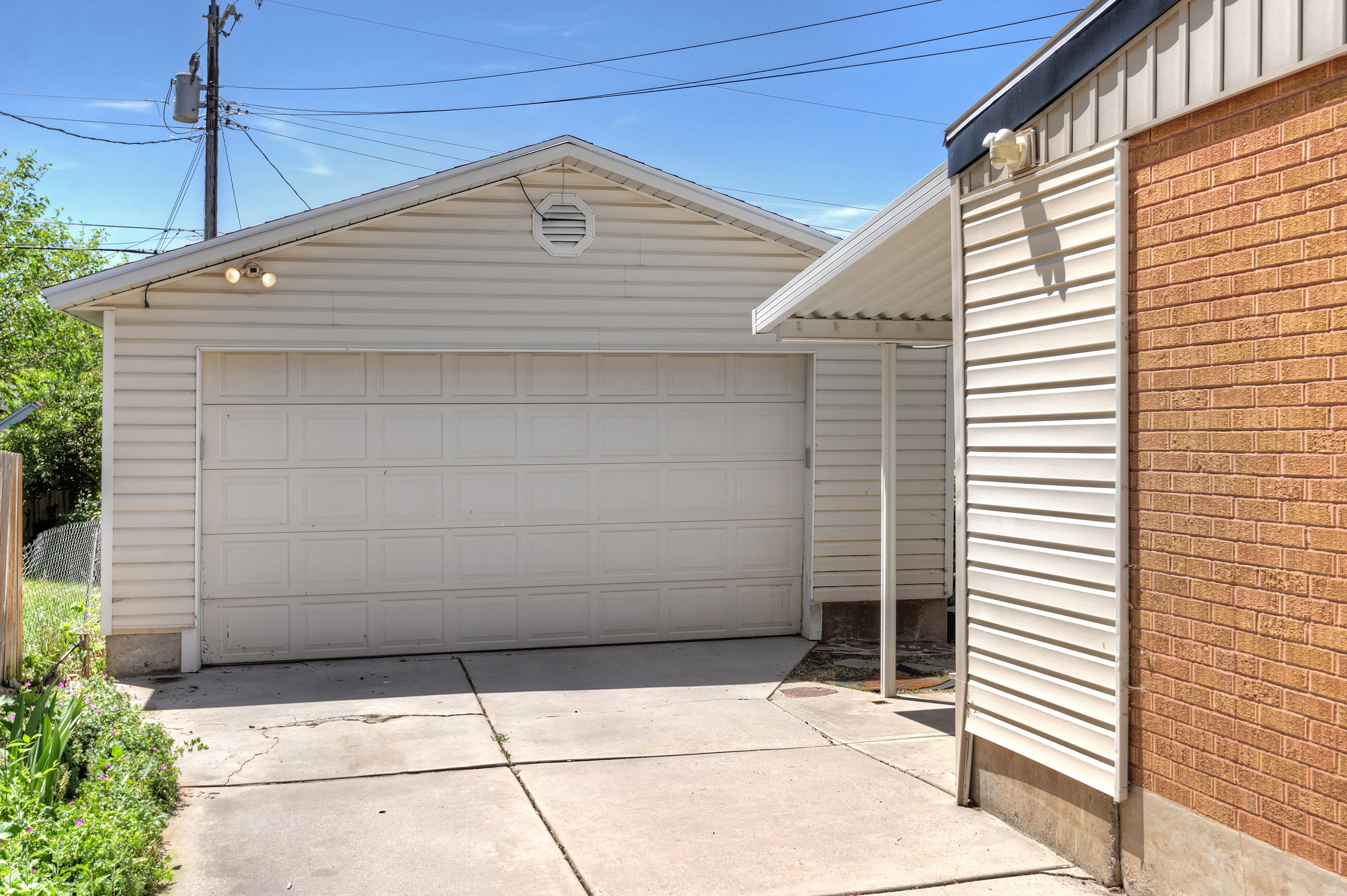 Detached garage with a paneled door, exterior wall lighting, and a front-facing gable with a louvered vent