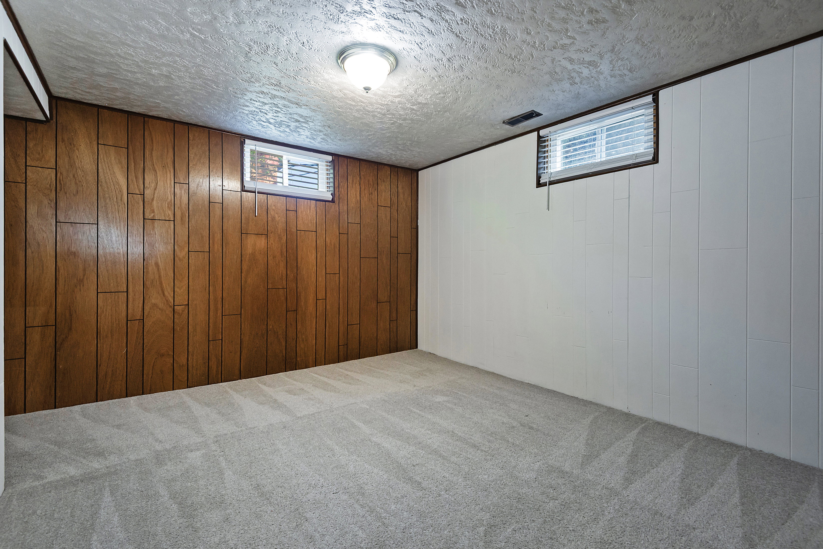 Carpeted room featuring wood paneling and white paneled walls