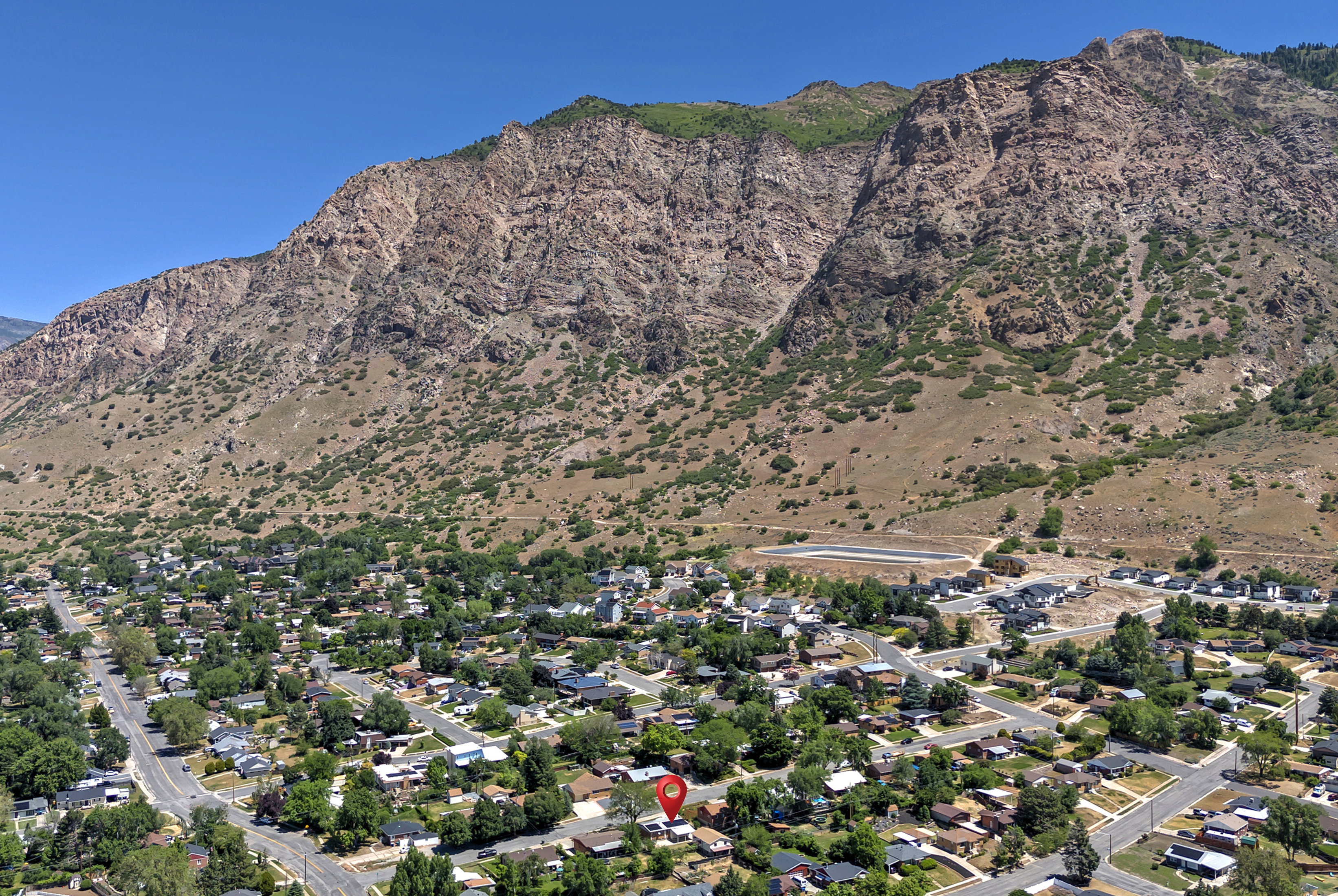 Expansive aerial perspective showcasing a residential neighborhood nestled at the base of a rugged mountain range