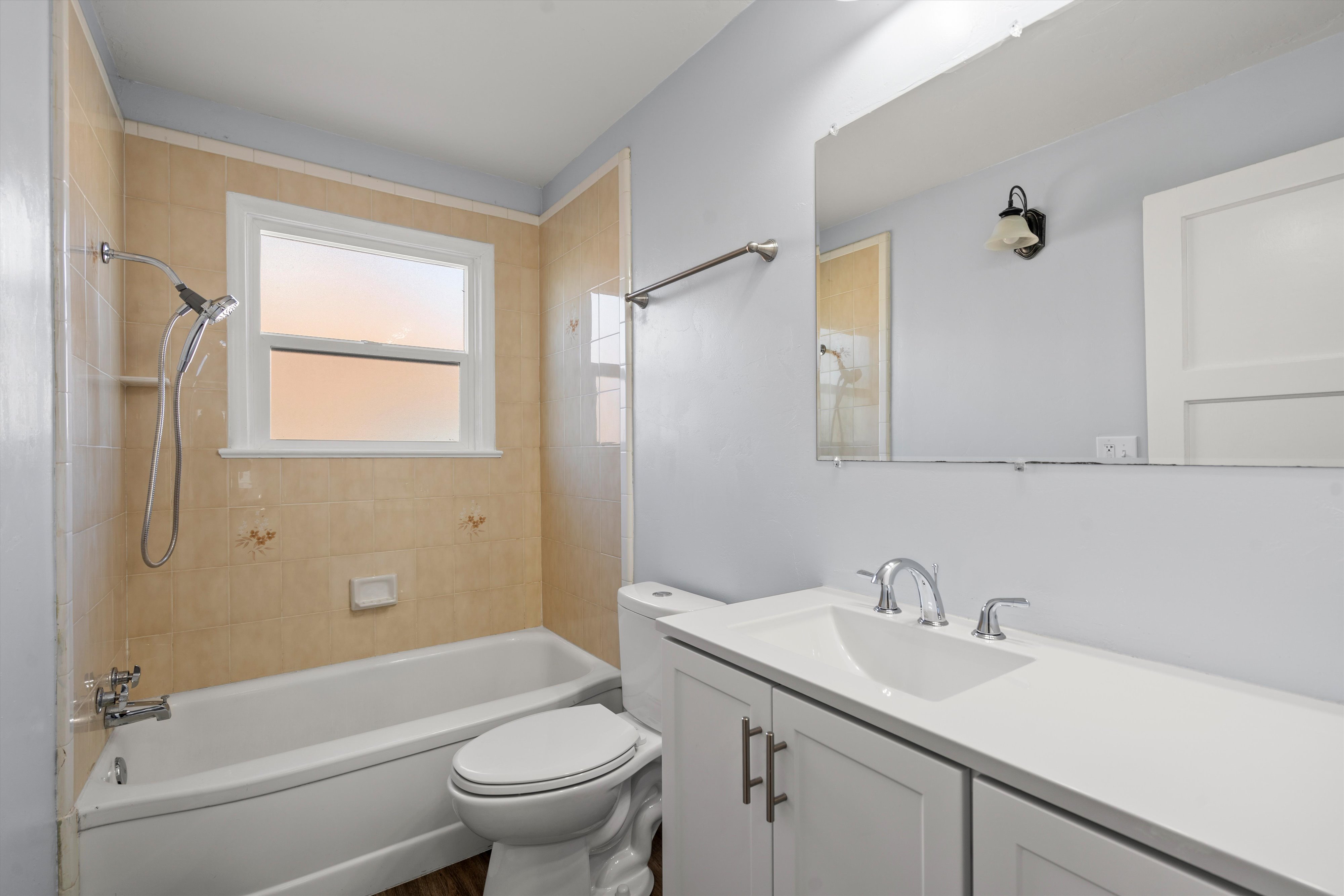 Full bathroom featuring a white vanity with integrated sink, chrome fixtures, and a frameless mirror