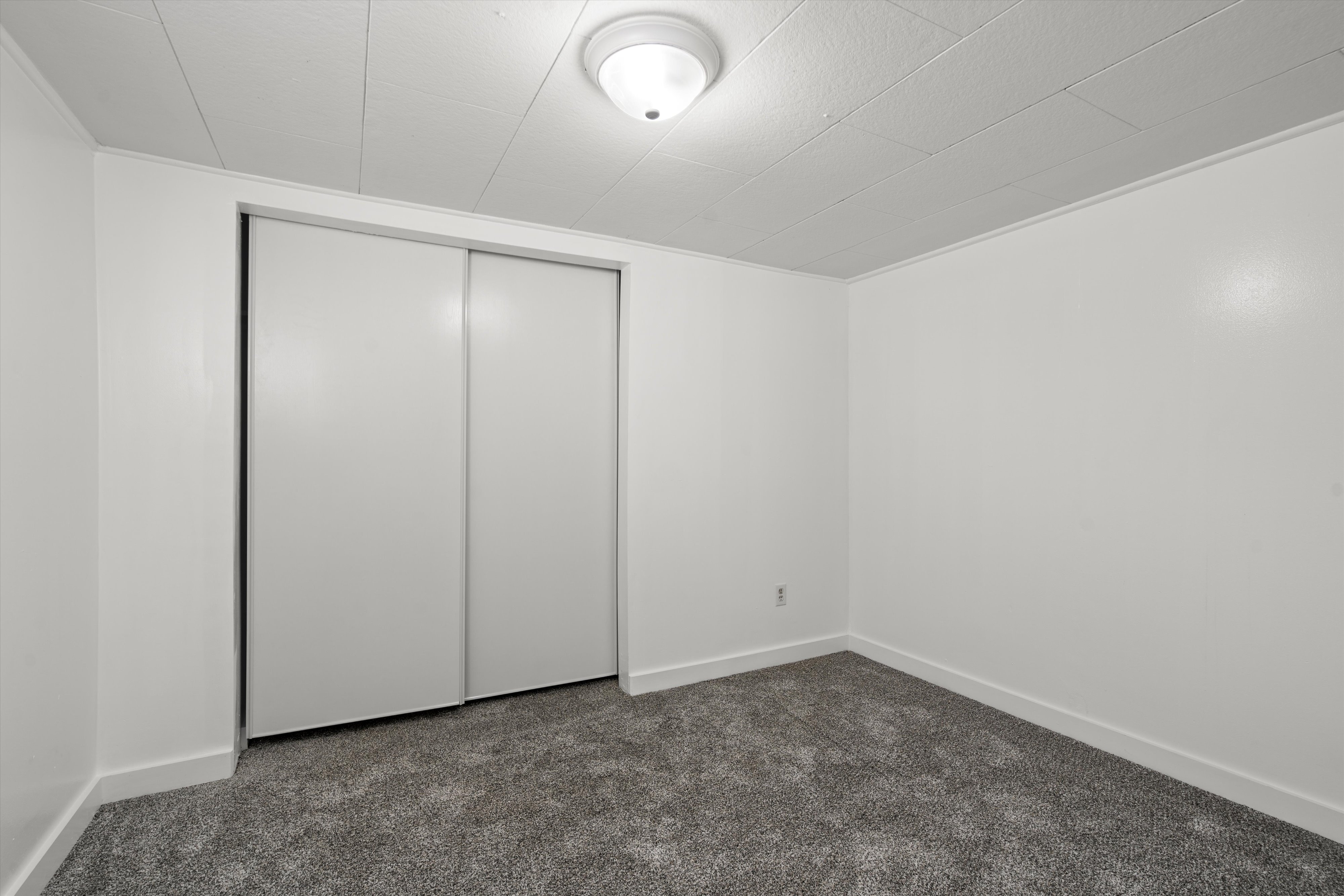 Spacious room with gray carpet flooring, white walls, and white baseboards