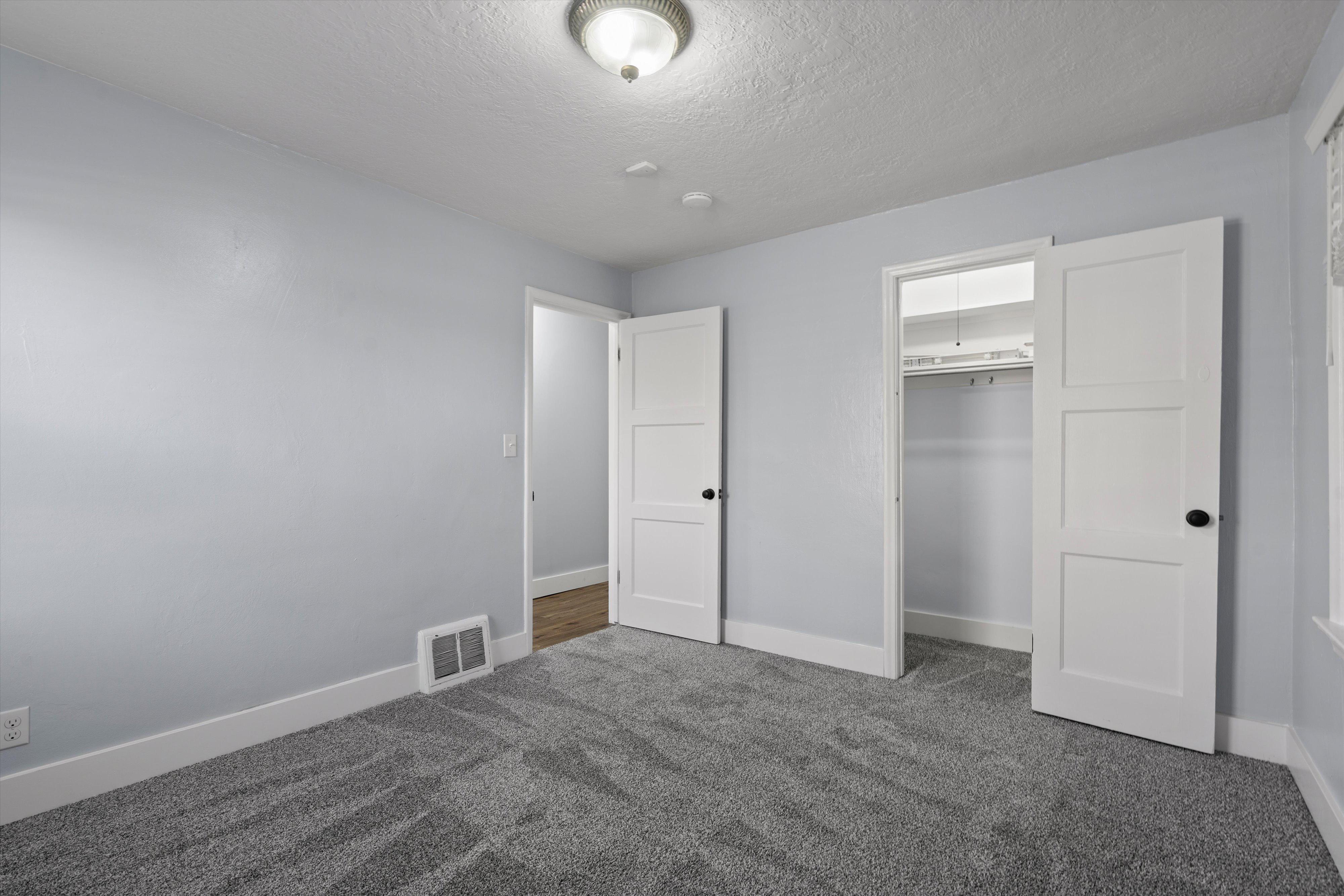 Carpeted room featuring light blue walls, white trim, and a ceiling light fixture