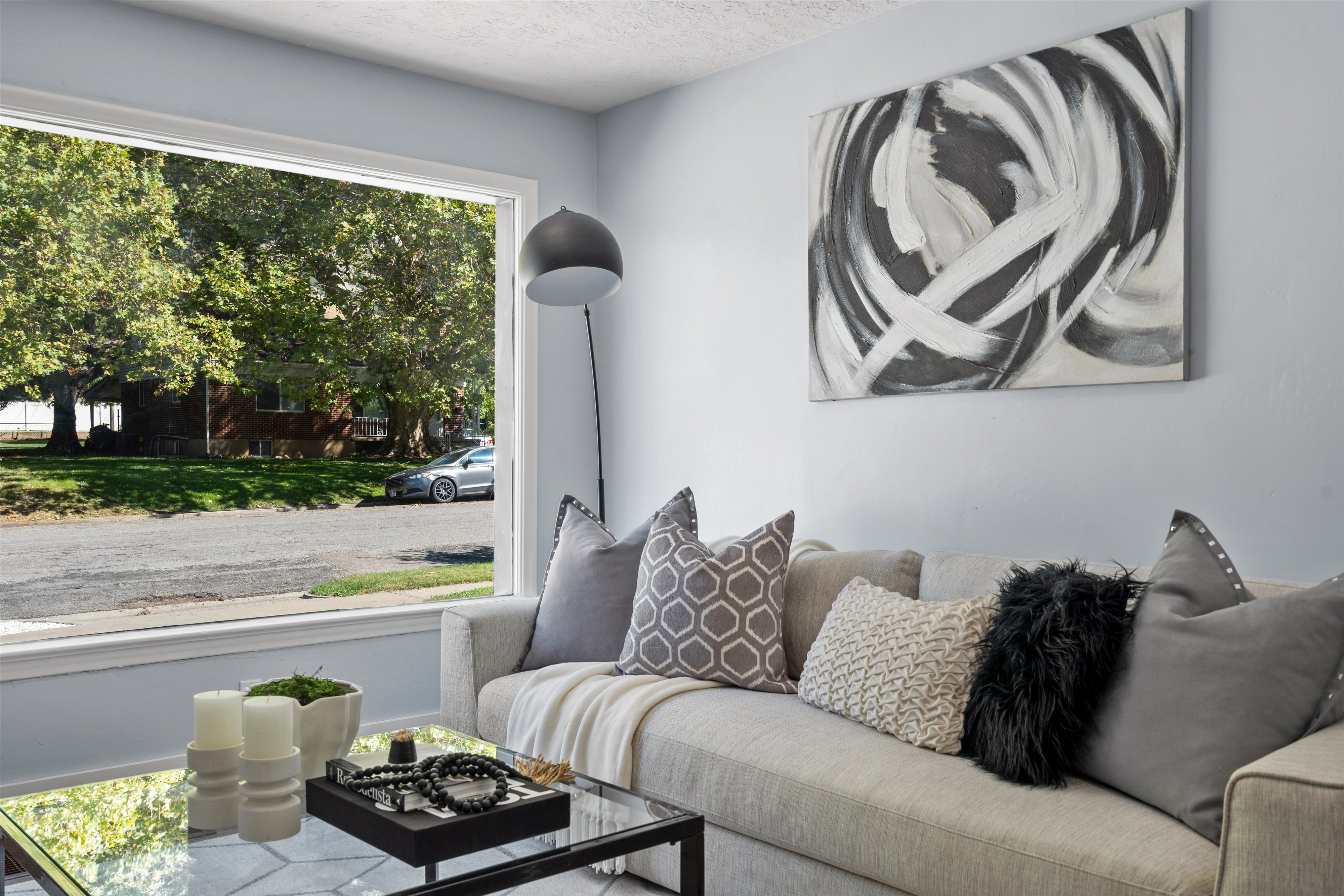 Spacious living area featuring a large picture window, pale blue wall paint, and a textured ceiling