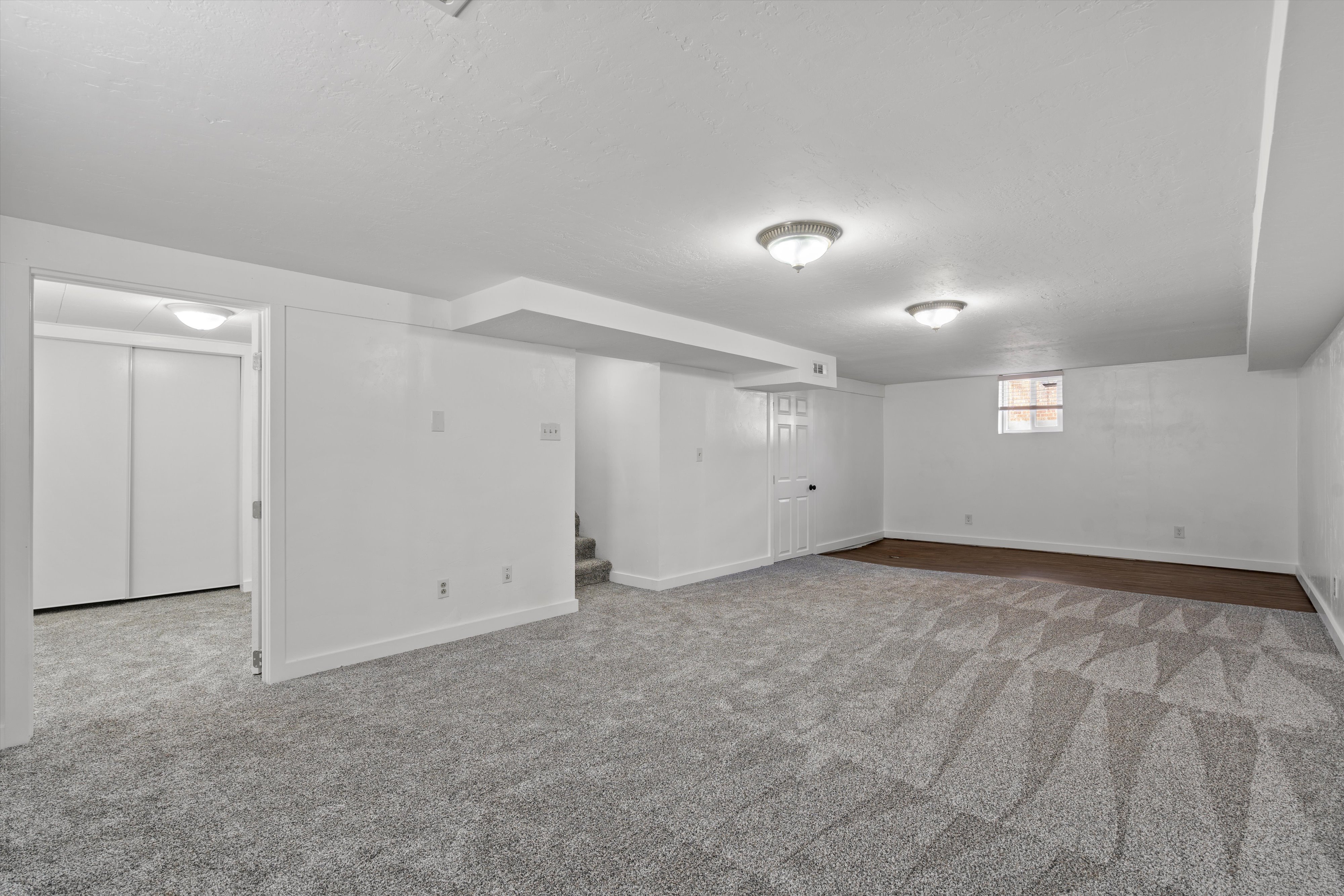 Spacious room featuring patterned carpet flooring, flush-mount ceiling lights, and white baseboards