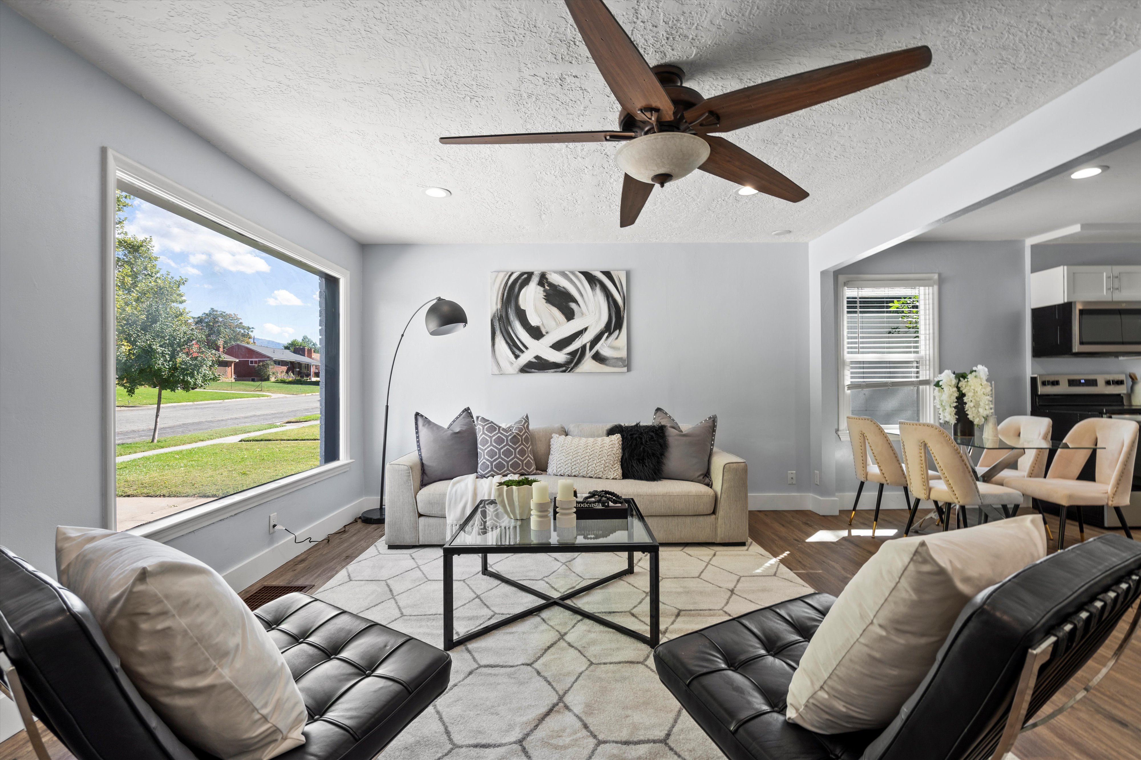 Open-concept living space featuring wood-finish flooring, a large picture window, and a contemporary ceiling fan