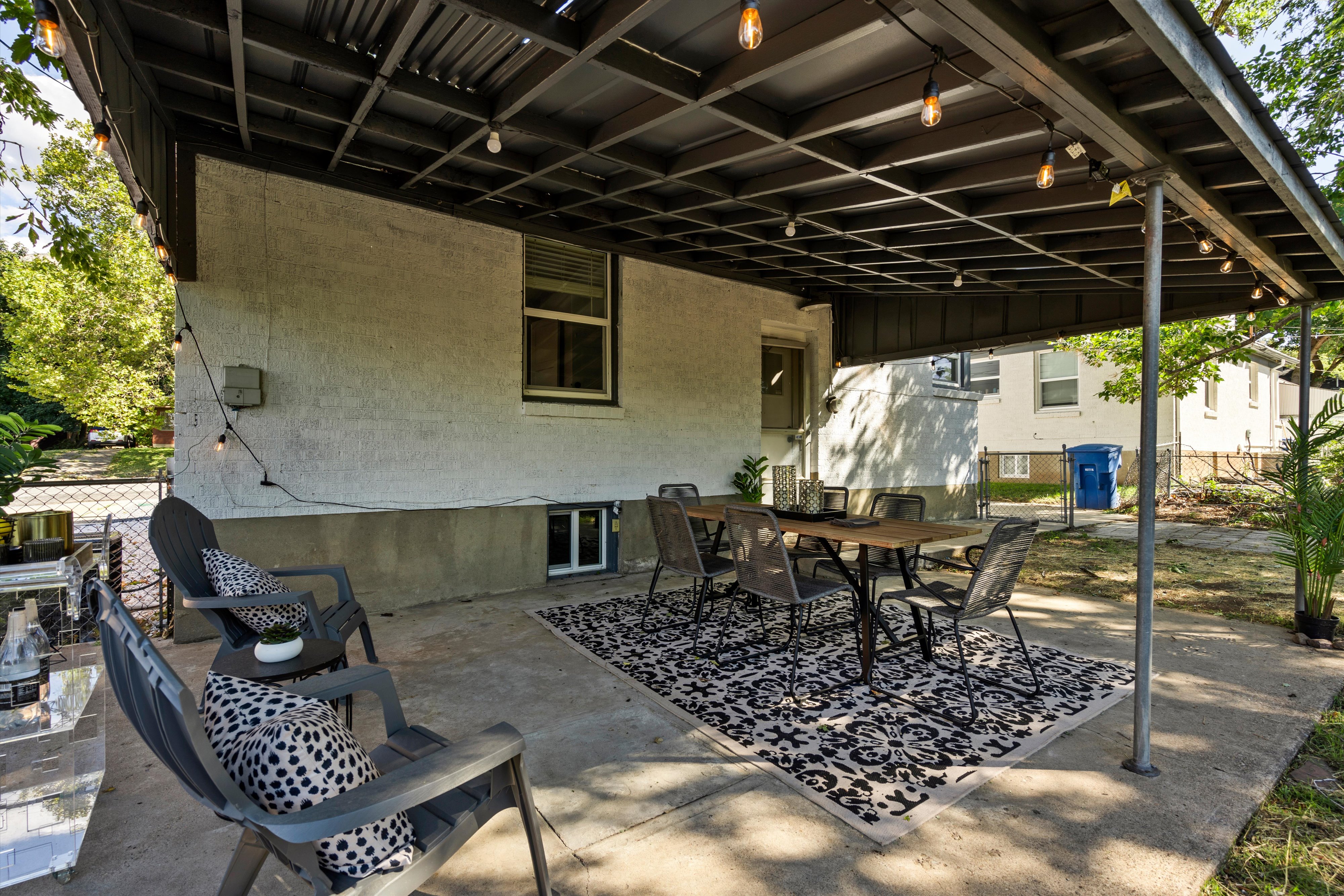 Expansive concrete patio with a covered pergola featuring string lighting