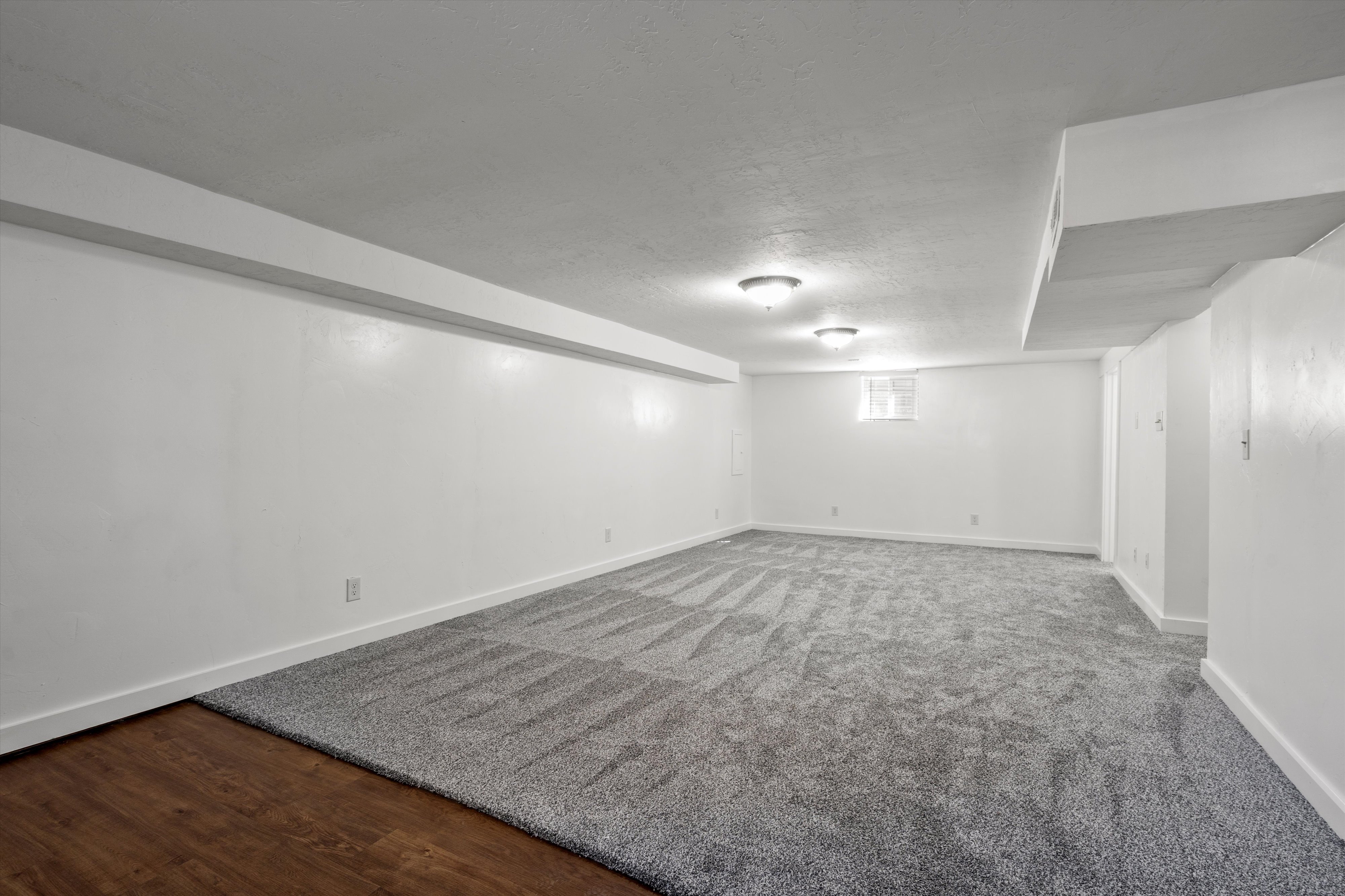 Spacious room featuring neutral carpeting with a subtle pattern, white painted walls, and recessed lighting fixtures