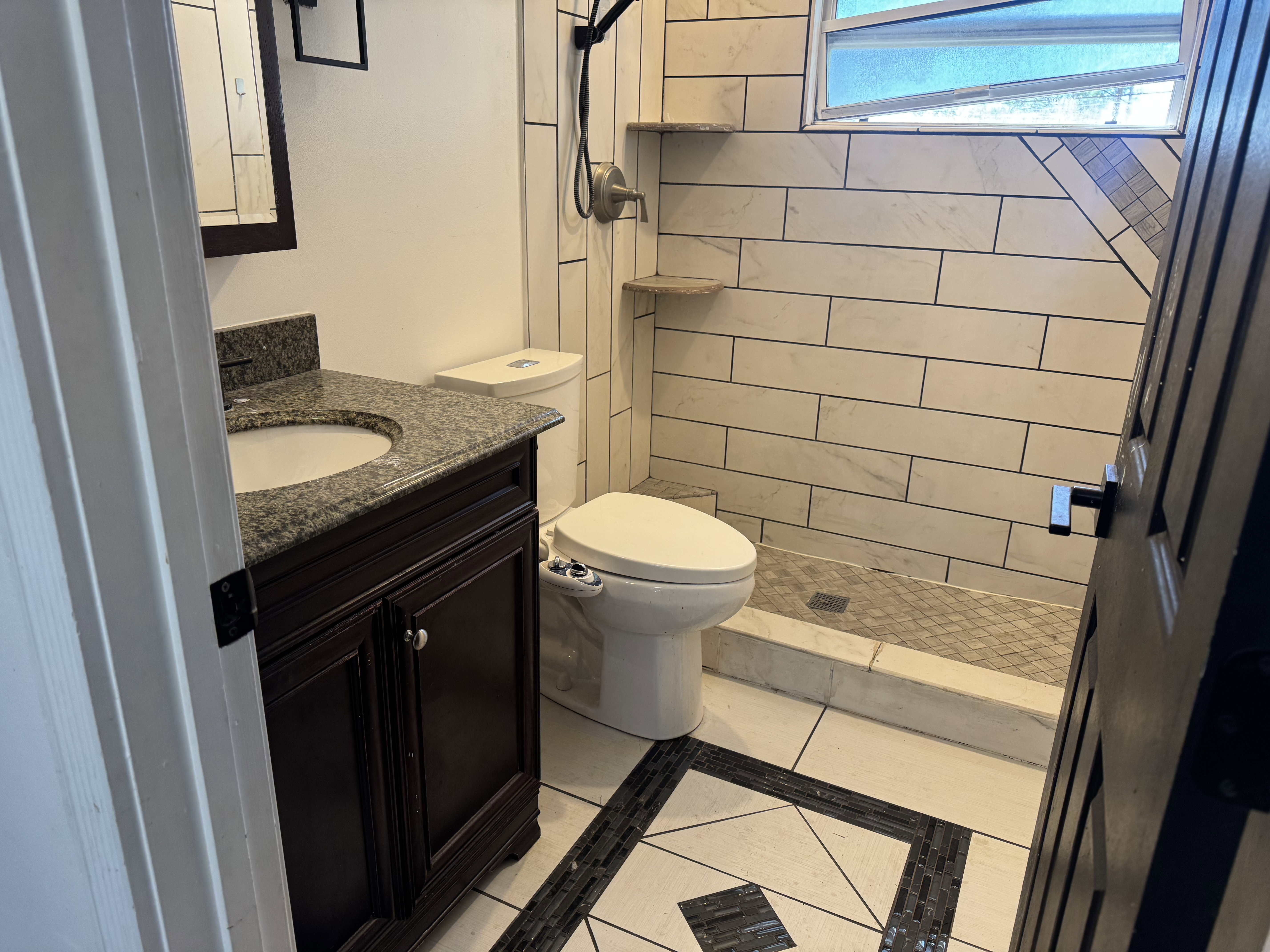 Bathroom featuring a dark wood vanity with a granite countertop, undermount sink, and dark-framed mirror