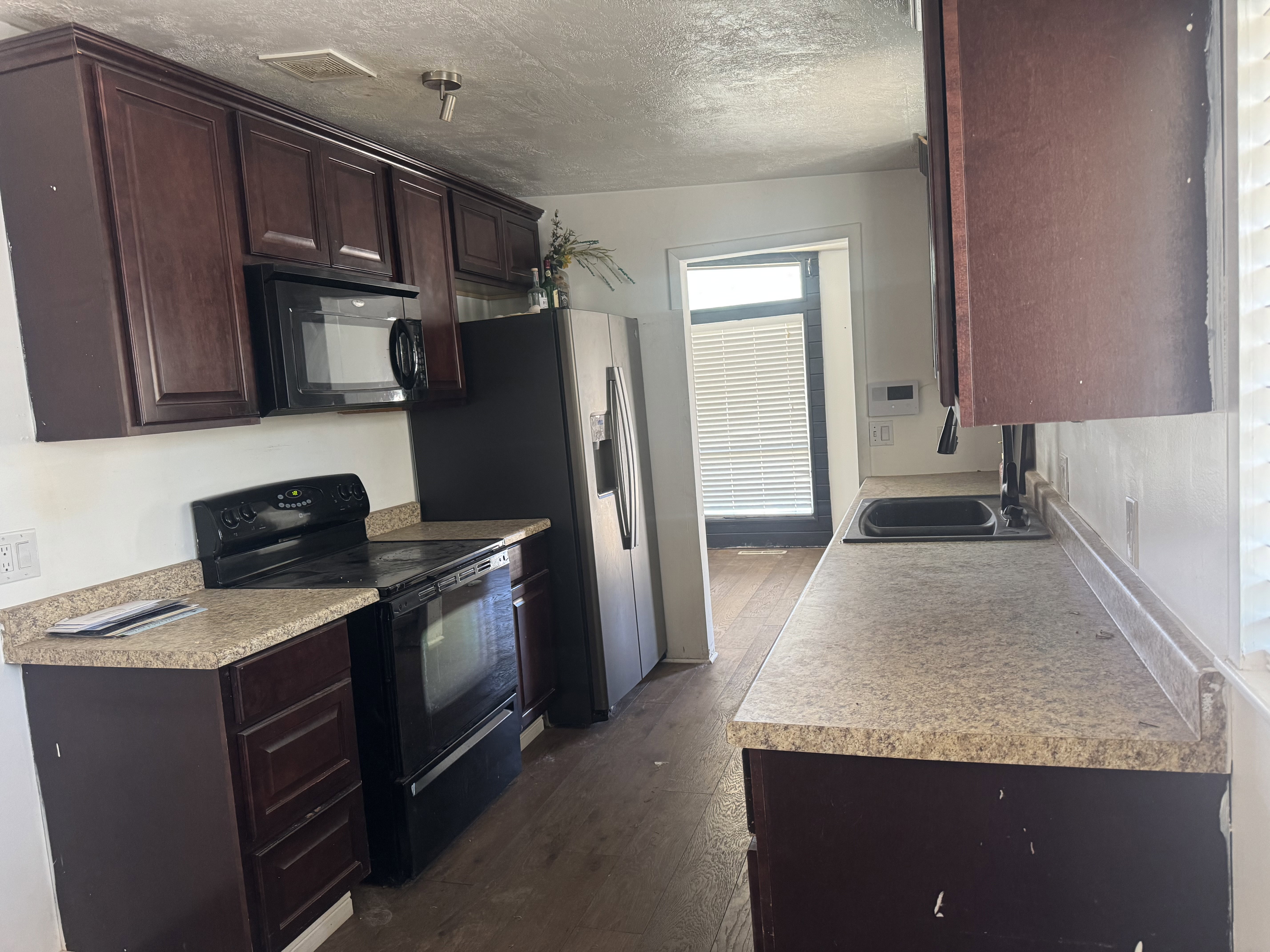 Kitchen featuring dark wood cabinetry, light speckled countertops, and wood-finish flooring