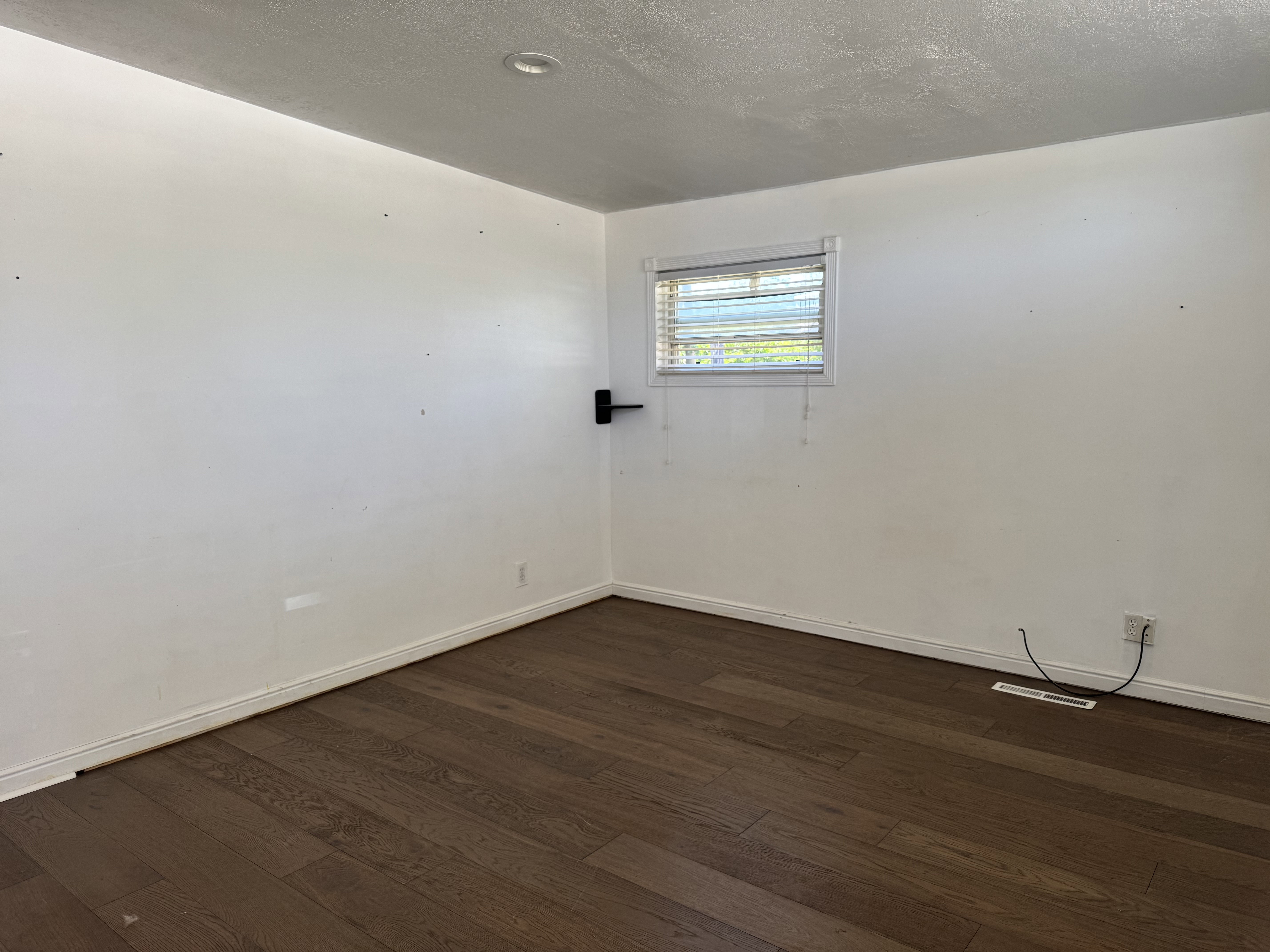 Interior room featuring wood-finish flooring, white painted walls, and white baseboards