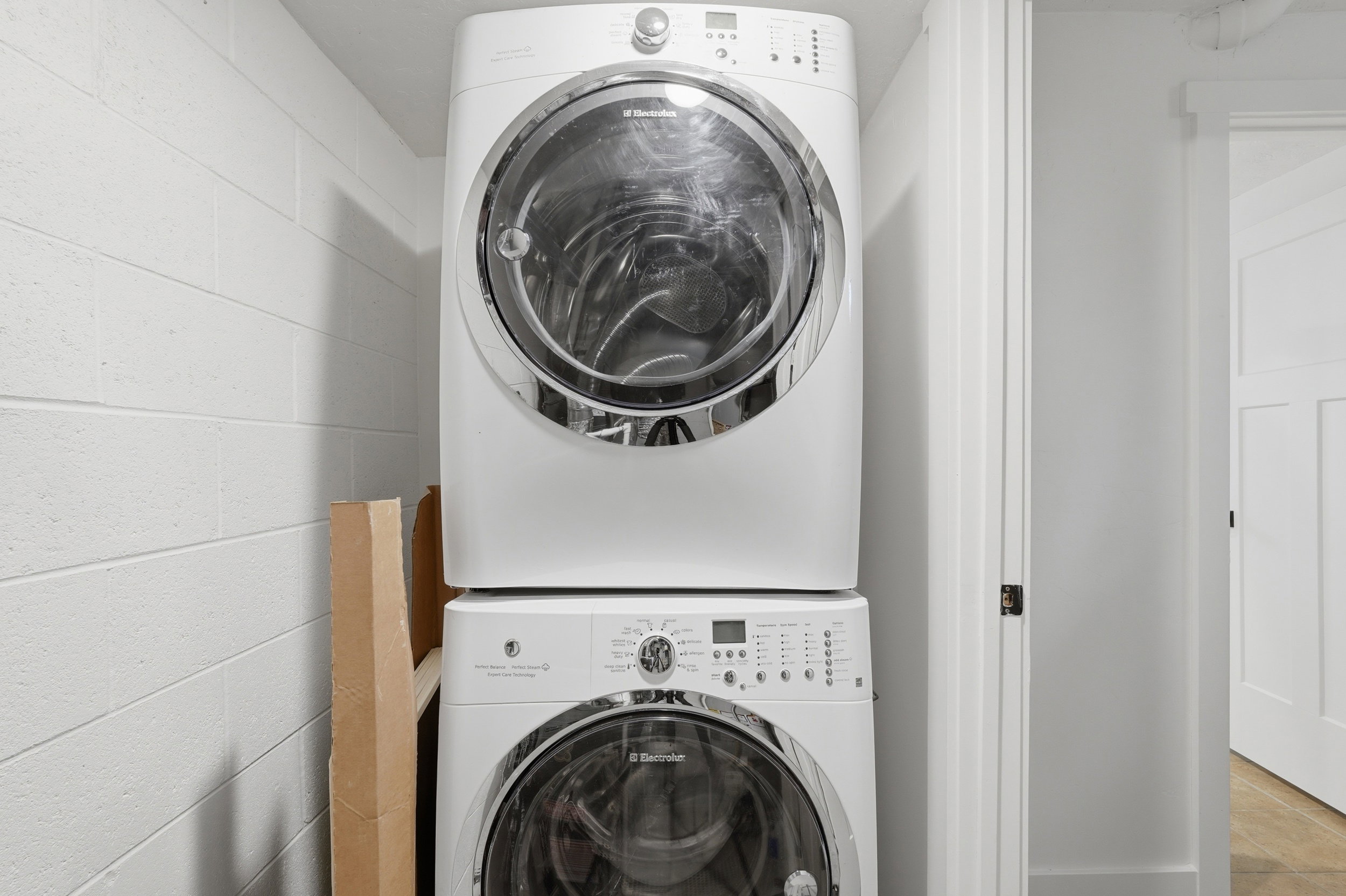 Stackable washer and dryer system with white finish, integrated into a utility area with white painted block walls