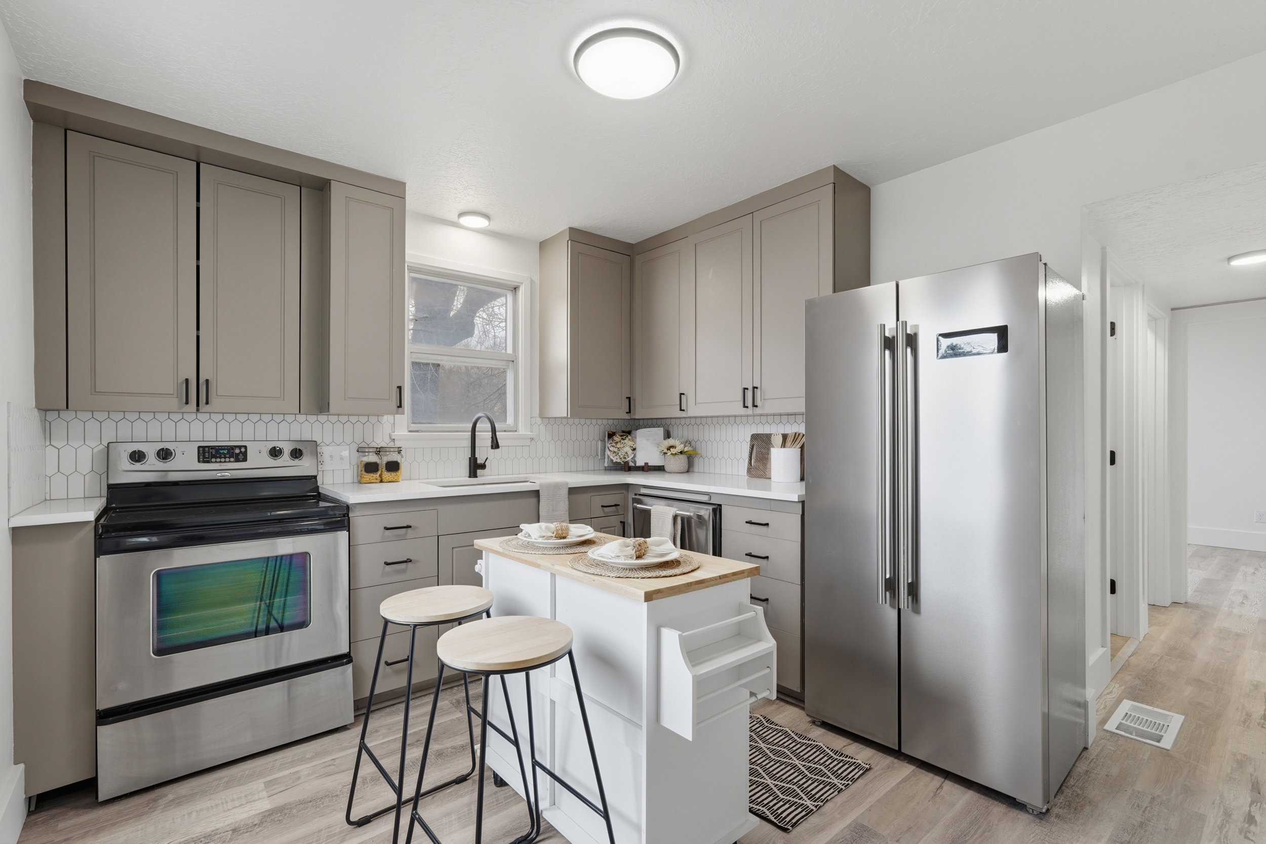 Contemporary kitchen featuring gray shaker-style cabinetry, stainless steel appliances, a white picket tile backsplash, and wood-finish flooring