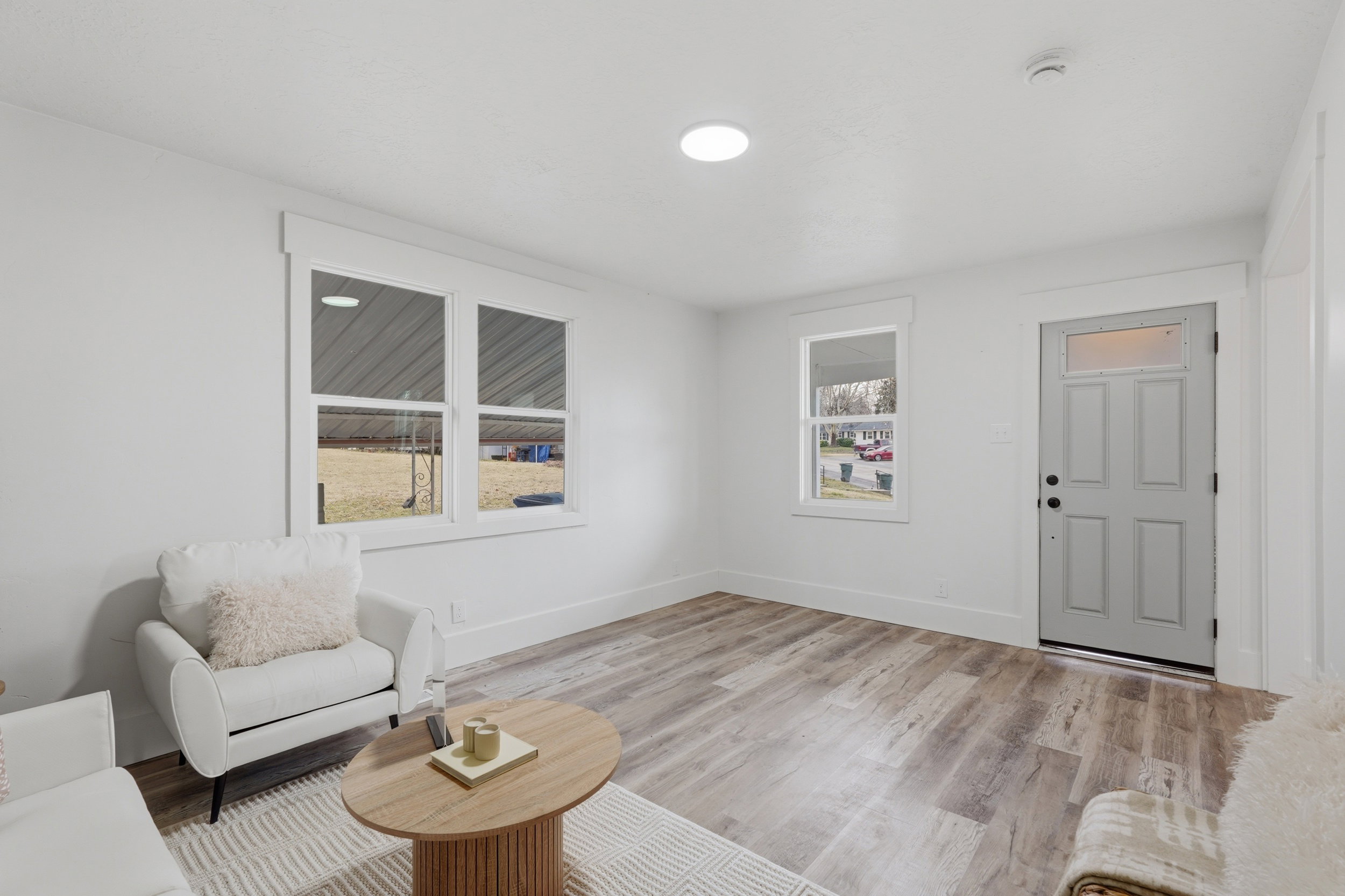 Spacious living area featuring light wood-finish flooring, crisp white walls, and a recessed ceiling light