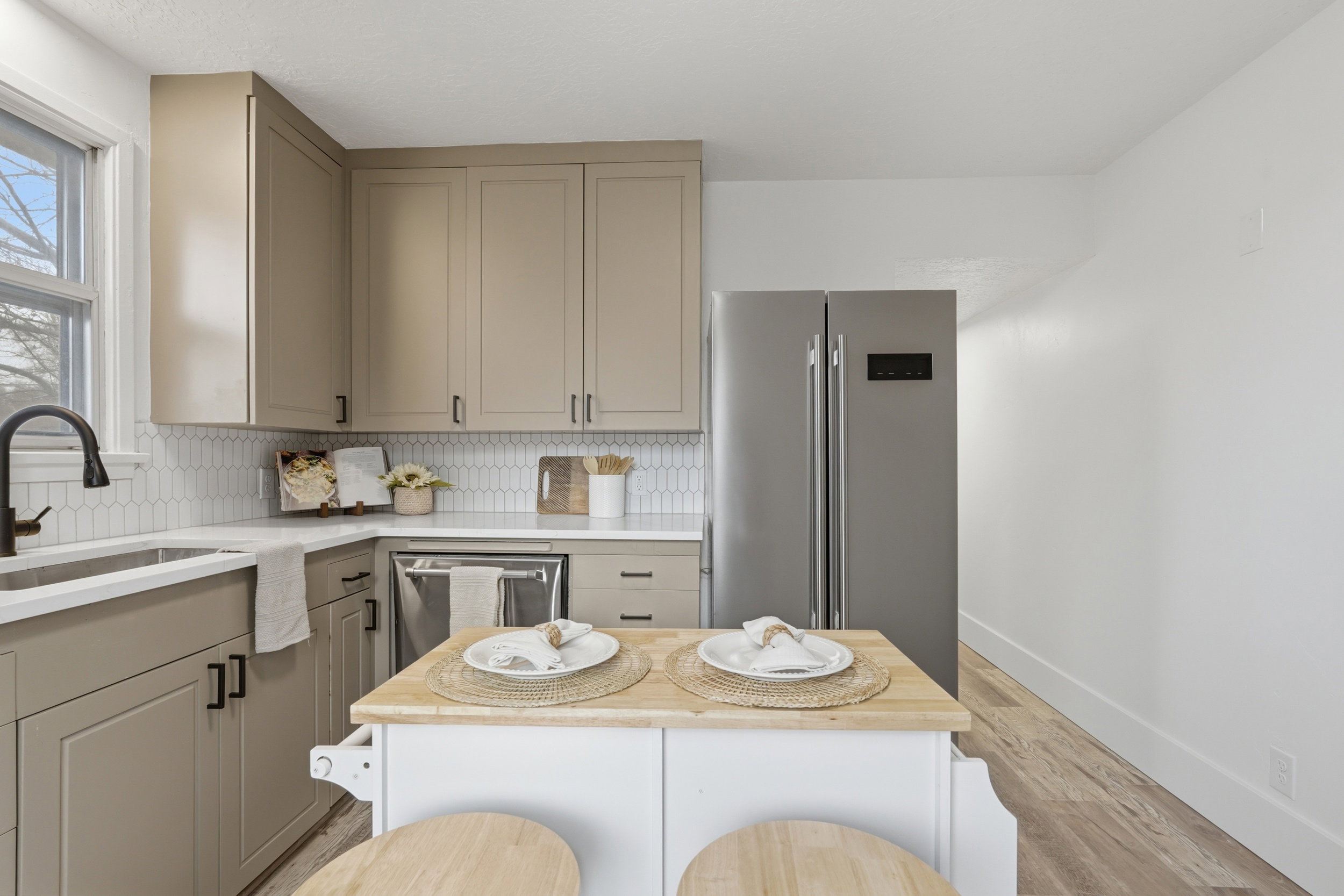 Kitchen featuring light-toned cabinetry, a white picket tile backsplash, white countertops, and wood-finish flooring