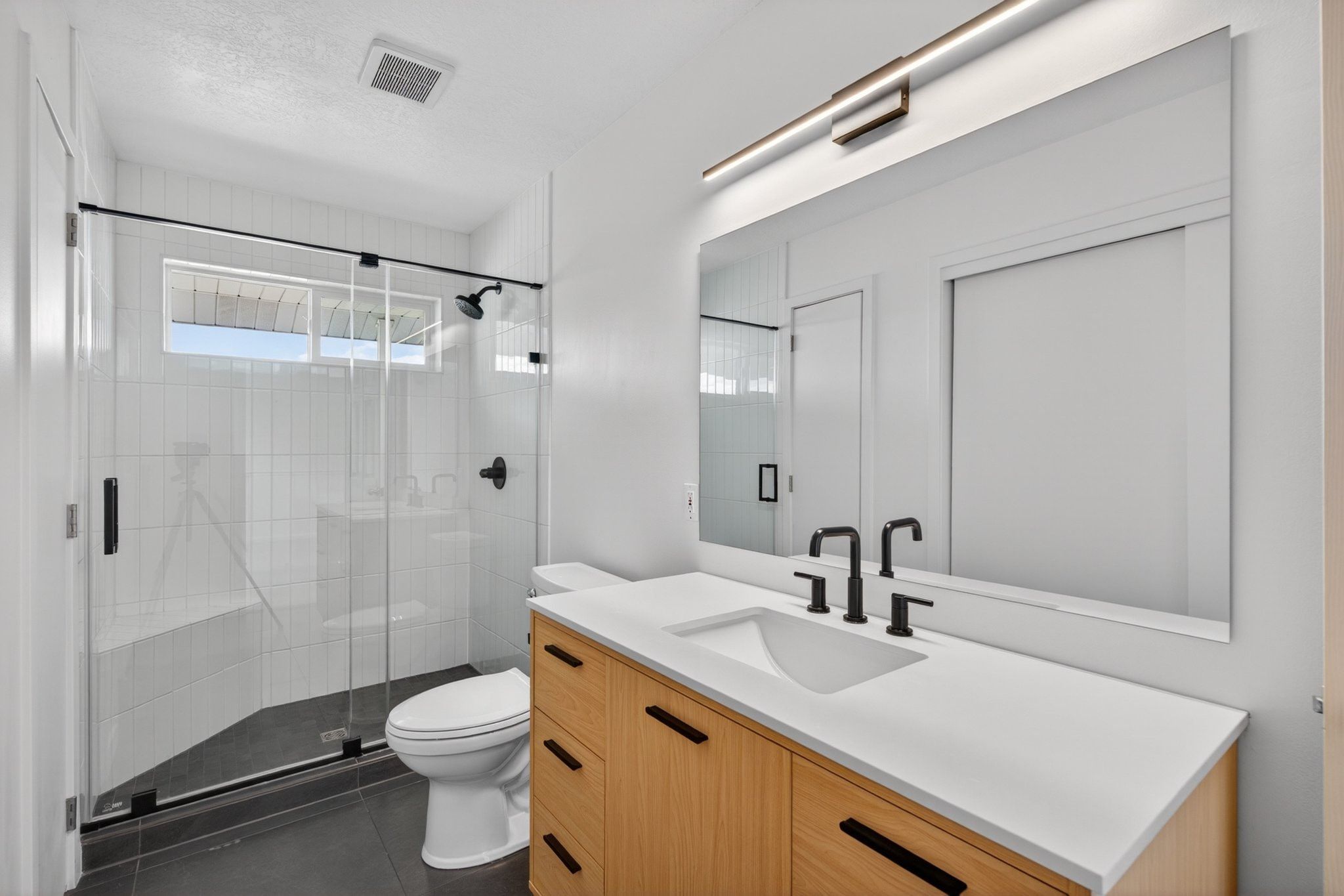 Modern bathroom featuring a wood-finish vanity with a white countertop and integrated sink
