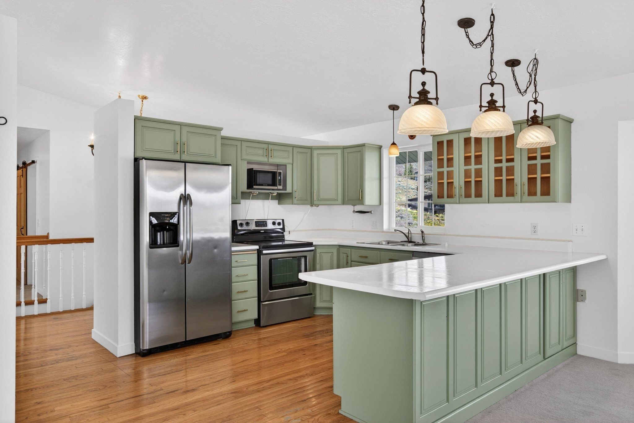 Kitchen featuring sage cabinetry, white countertops, stainless steel appliances, and wood-finish flooring