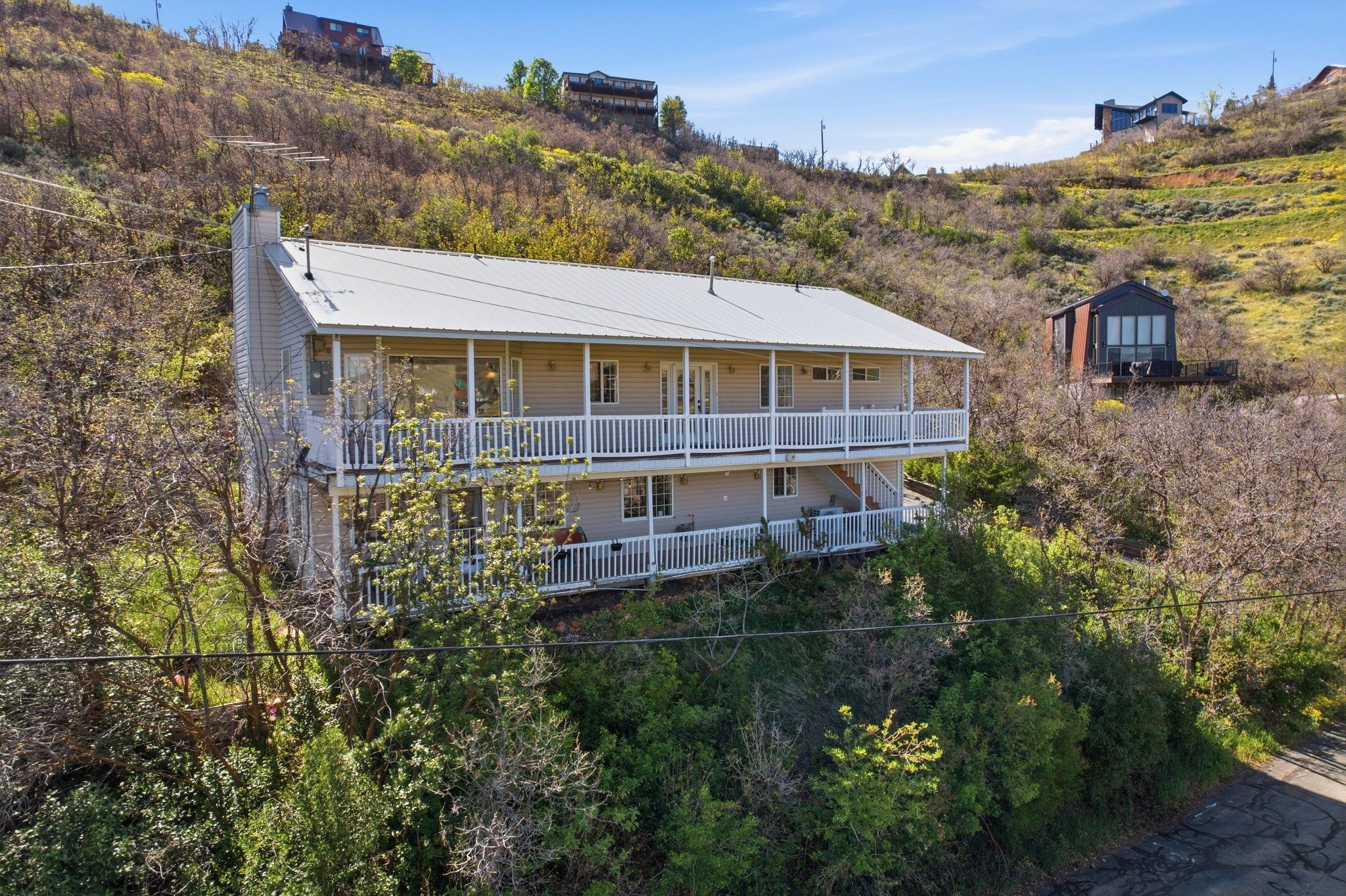 Two-story residence featuring a metal roof, light-colored siding, and dual-level covered balconies with white railings
